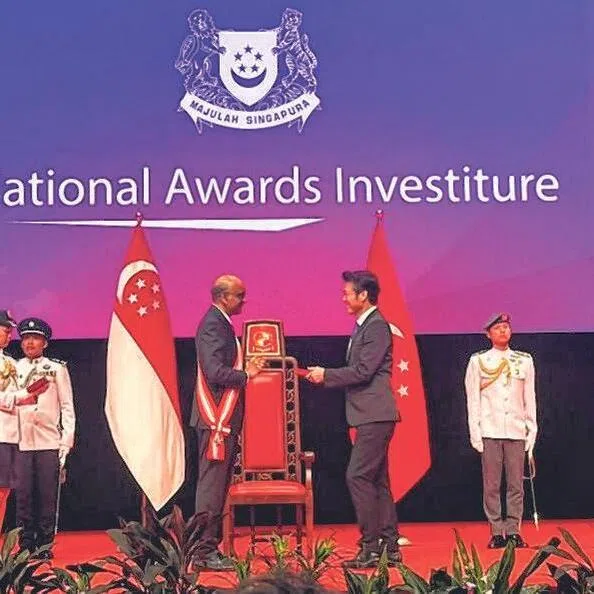 郑各评从总统尚达曼手中接过勋章。（郑各评提供）