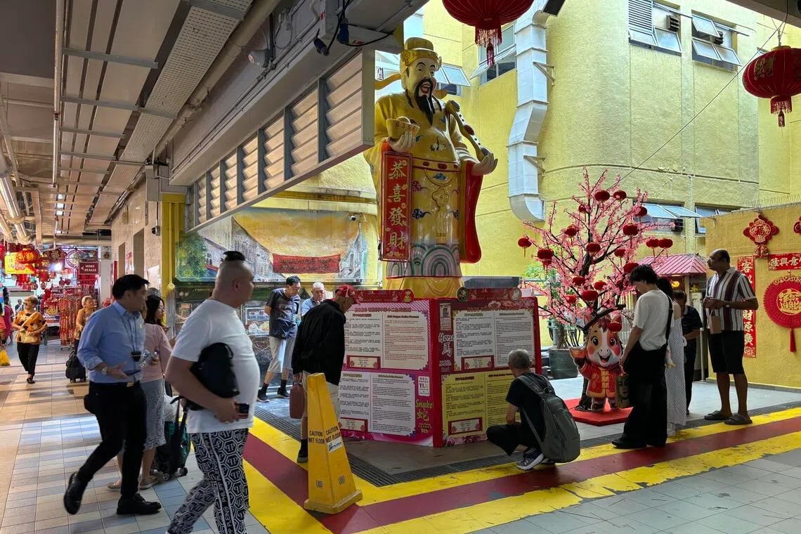 《新明日报》记者星期二（1月6日）走访牛车水大厦时观察到，由于生肖运程的位置偏低，有人得蹲在斜坡或台阶附近，仔细阅读上面的内容。（李宣進摄）