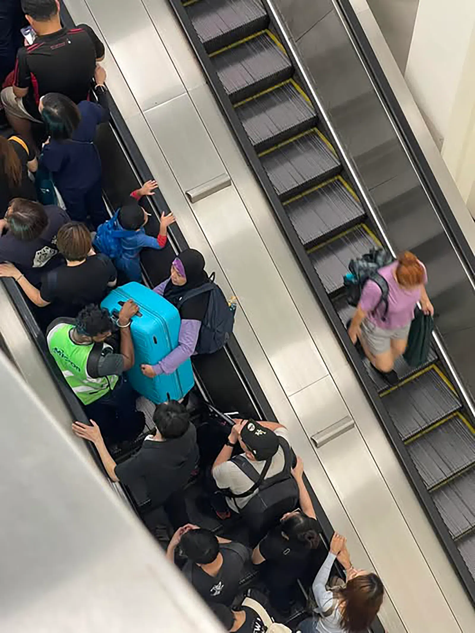 有人拍下暖心一幕，两名男子帮一名妇女将行李箱抬上扶梯。（取自脸书）