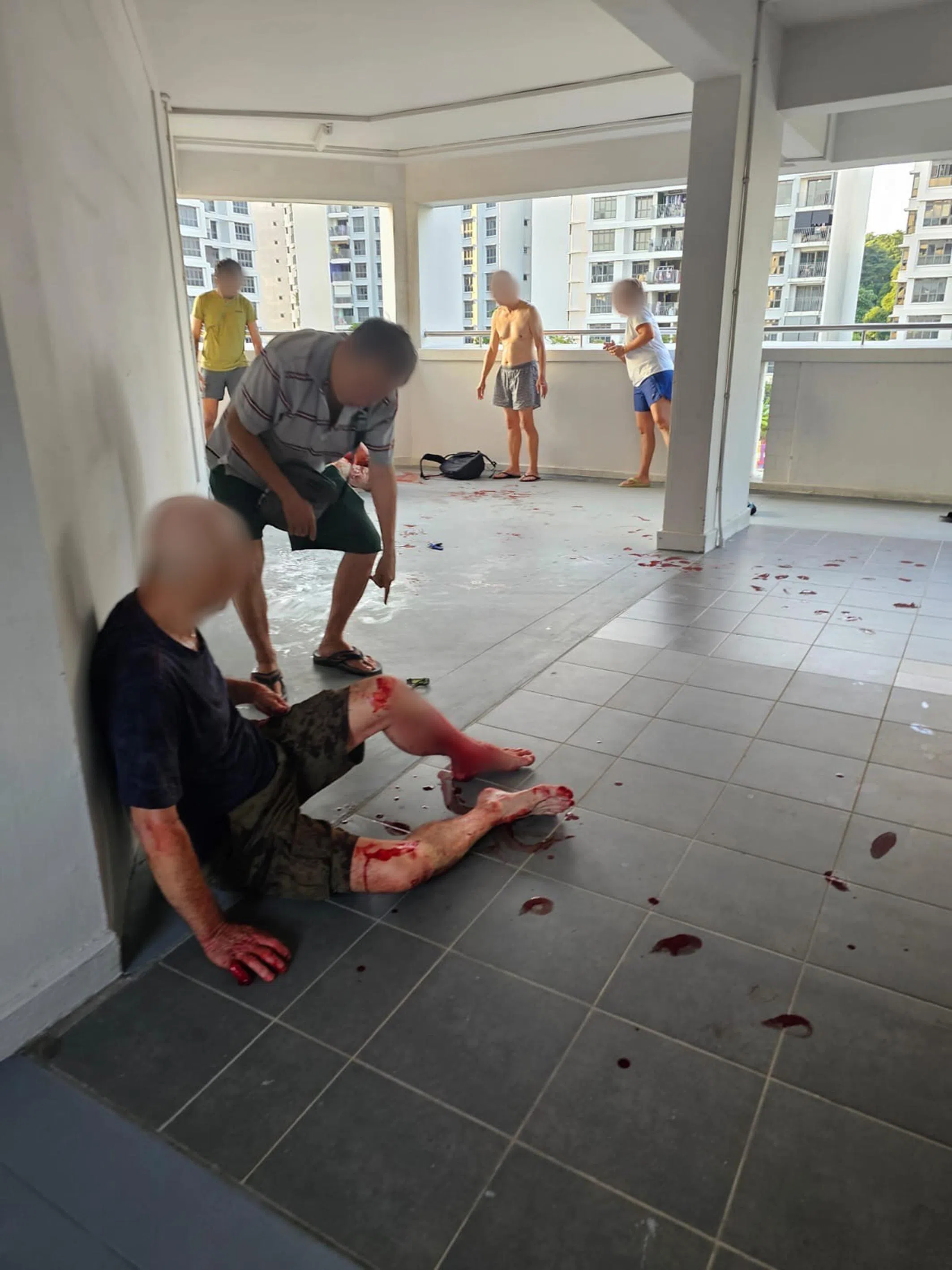 遭居民闻声赶来劝阻后，嫌凶（左）浑身是血靠着墙壁坐在地上。（受访者提供）