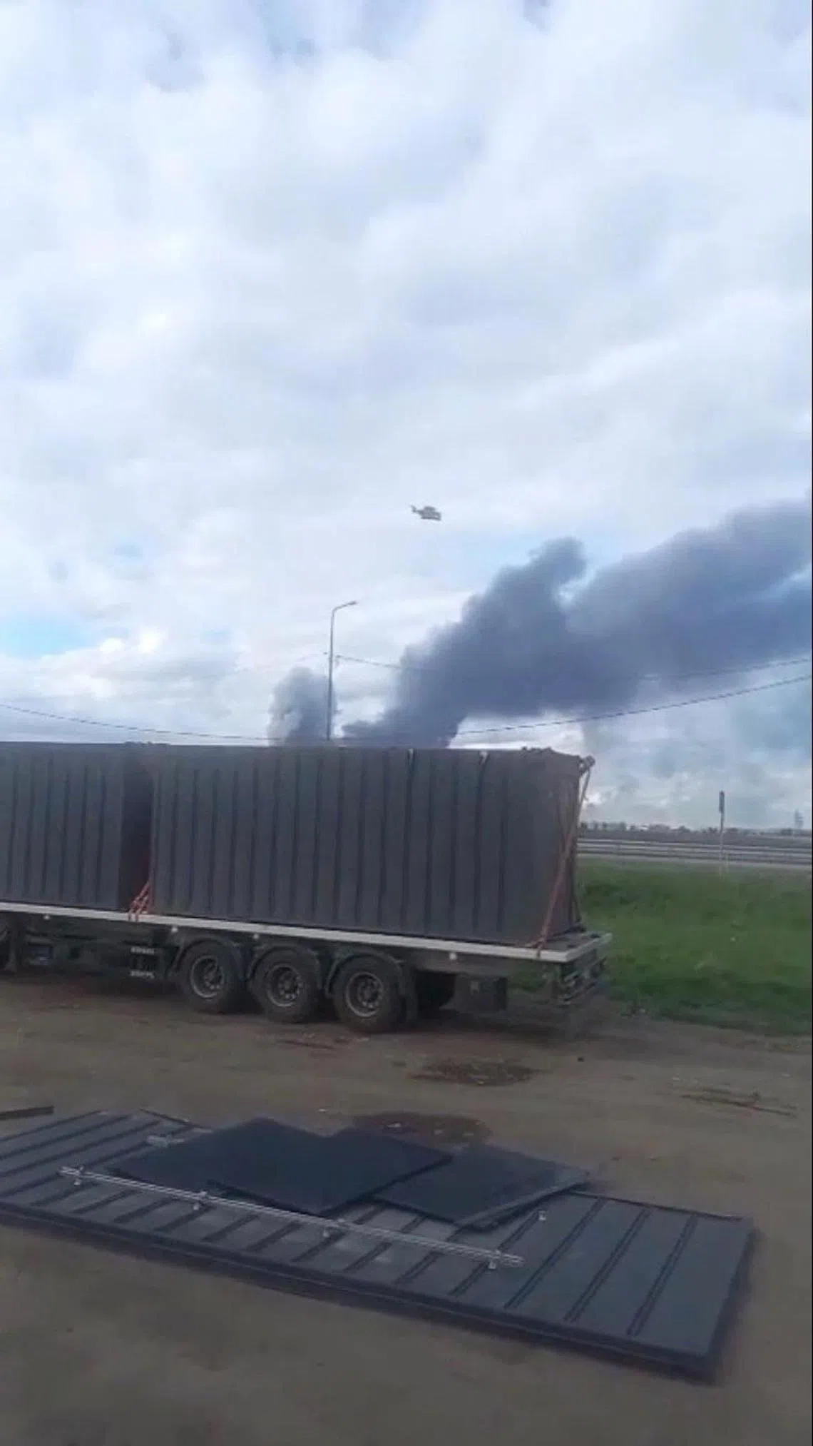 6月1日发布的这一社交媒体视频截图显示，一辆卡车行驶到俄罗斯伊尔库茨克州马尔塔空军基地周边时，一架无人机从卡车上装载着的木棚飞出去，背景可看到烟雾弥漫。（路透社）