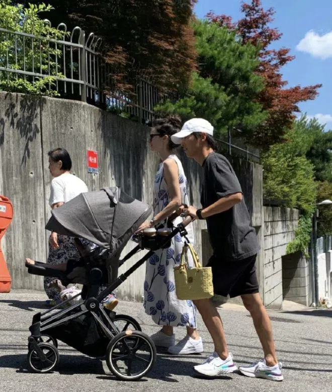 带着鸭舌帽的宋仲基（右一）与老婆凯蒂（右二）带着一岁儿子和爱犬（图下方，婴儿车右边）外出散步。（互联网）