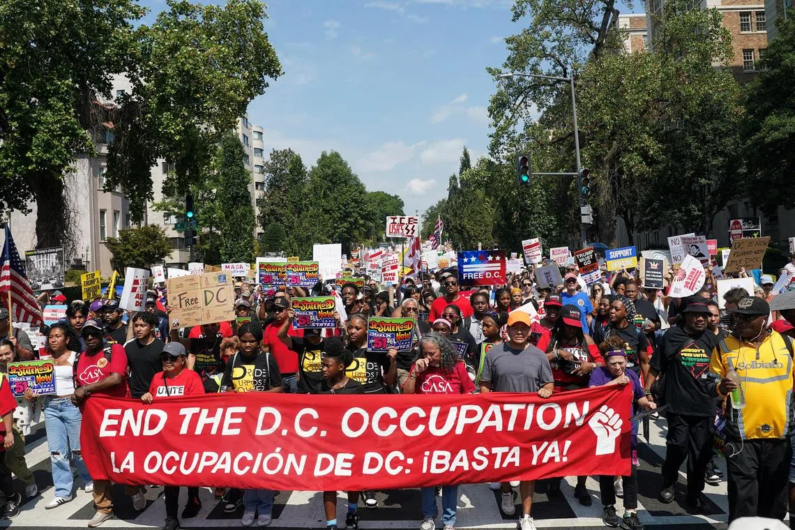 华盛顿特区的民众星期六举行示威活动，反对特朗普向当地派遣国民警卫队。示威者拉起英西双语横幅，上面写着：“结束占领华府！”（路透社）