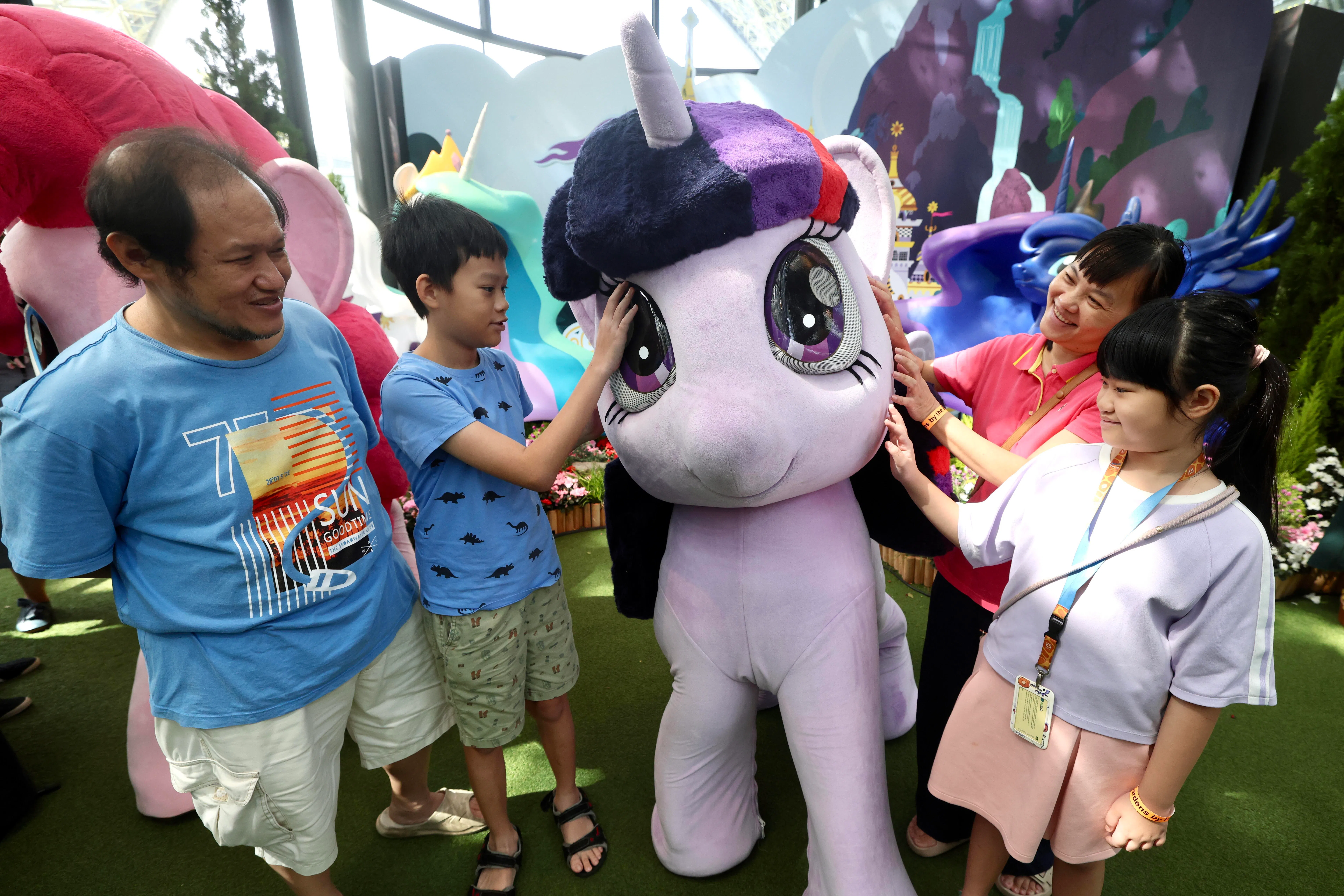 从事学前教育工作的职总会员陈洁（右二）一家四口首次参观奇幻花园，并和小马宝莉中的角色玩偶合照留念。（陈斌勤摄）