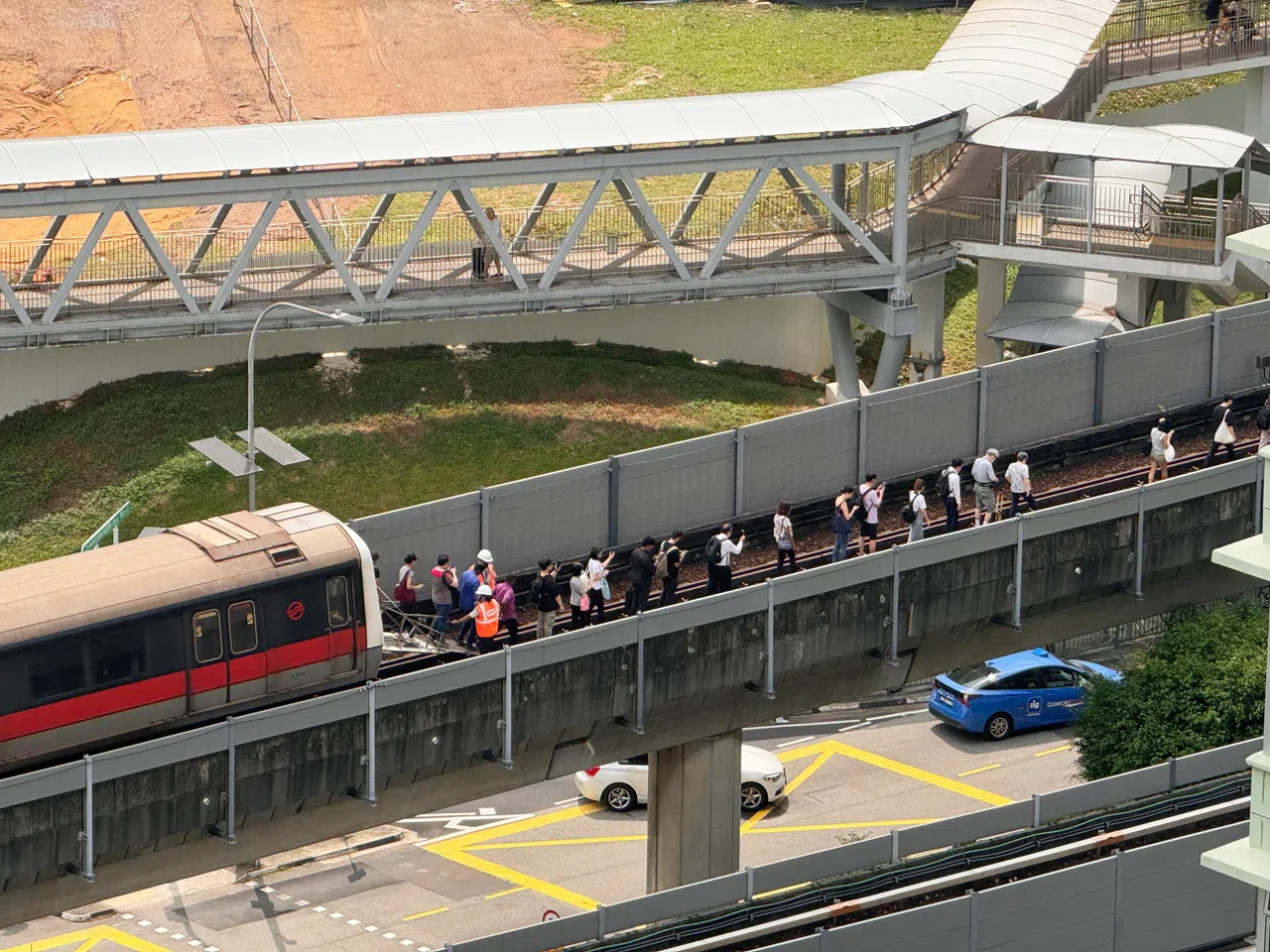 列车因故障停滞，工作人员引导乘客走向地铁站月台。（蓝靖仪摄）