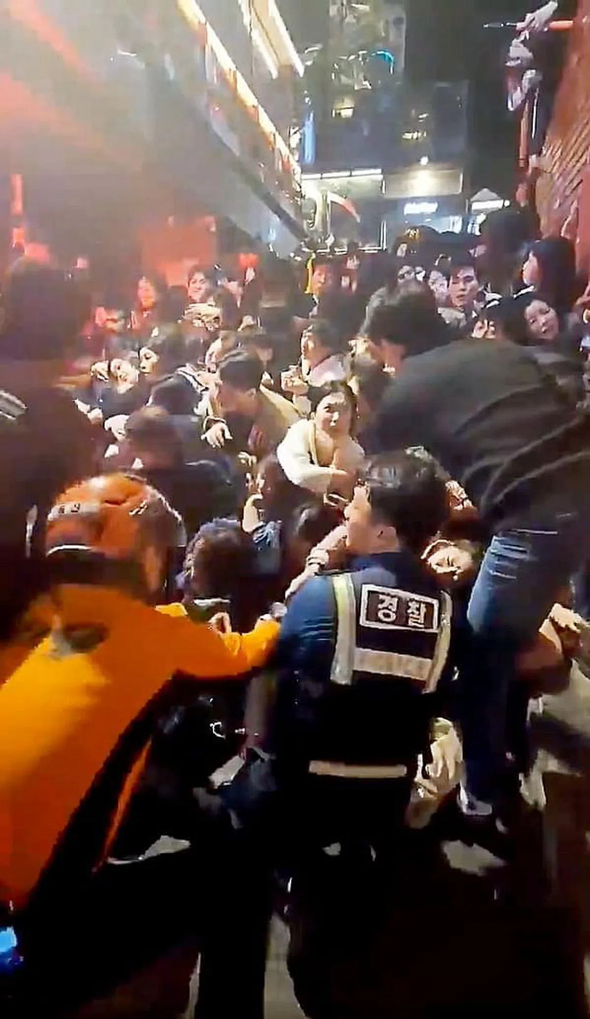 网上流传的现场画面显示，许多人被挤压到动弹不得，救援人员要抢救却无法把人拉出来。（视频截图）