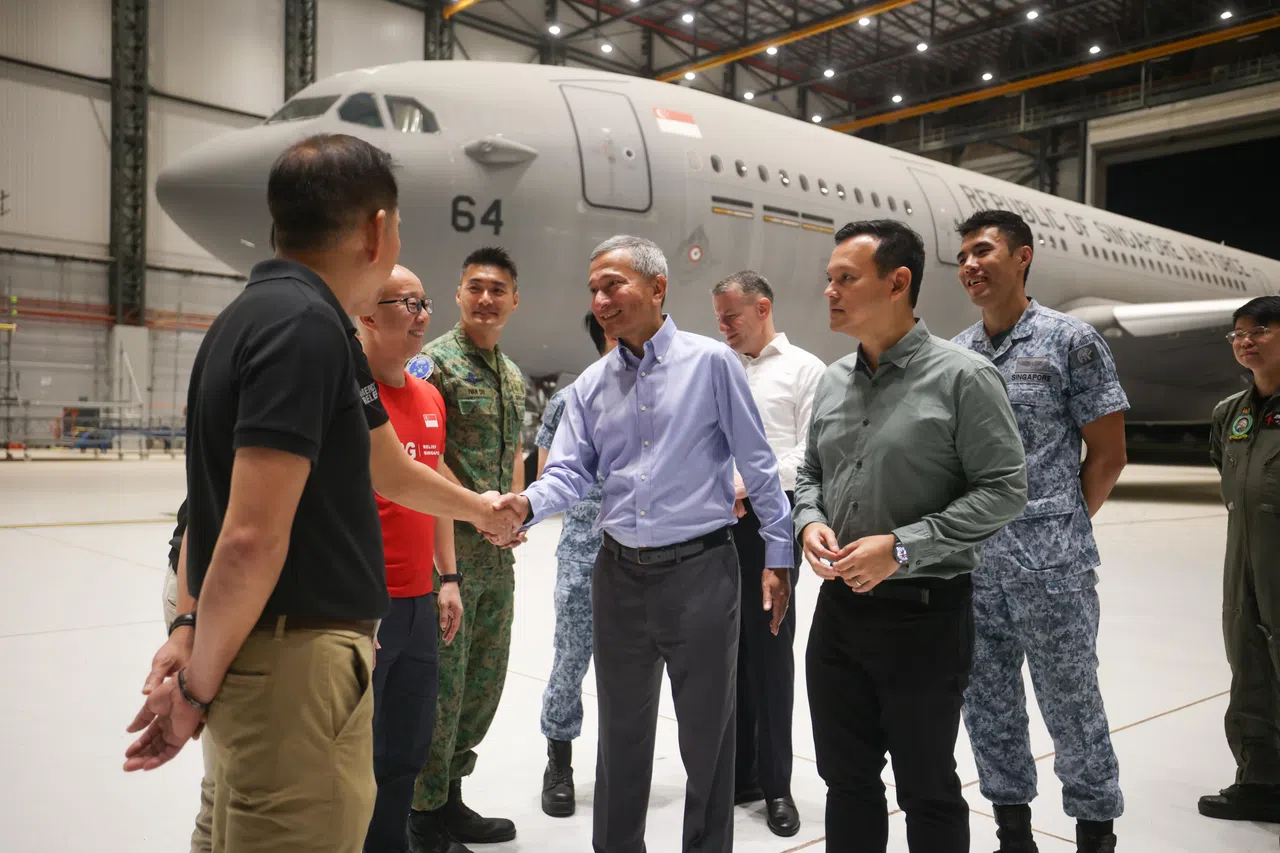 外交部长维文医生（前排右二）星期三上午到樟宜空军基地送行时，与准备飞往约旦的工作人员和非政府组织代表交谈。人力部兼国防部高级政务部长扎吉哈（前排右一）则随同运送团队一起飞往约旦。（关俊威摄）