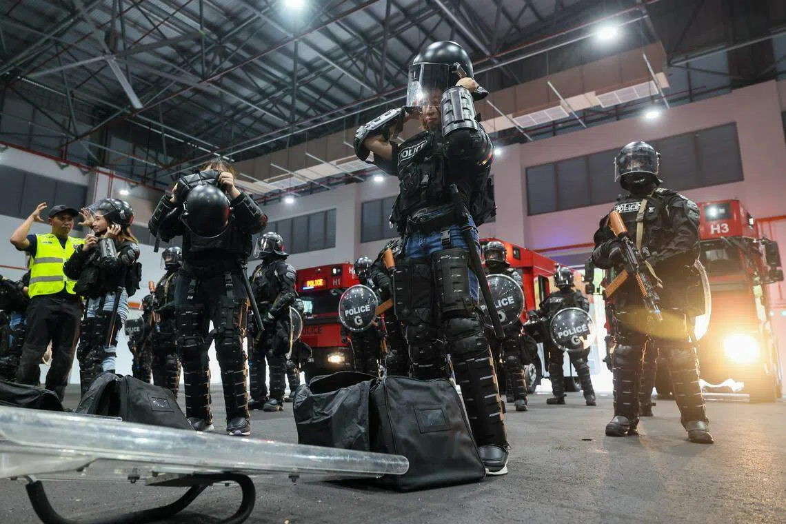 《联合早报》记者（前排右一）体验当一日镇暴队队员，必须在六分钟内穿好部分装备，然后和队员一起镇压“暴民”。（卓祾祎摄）