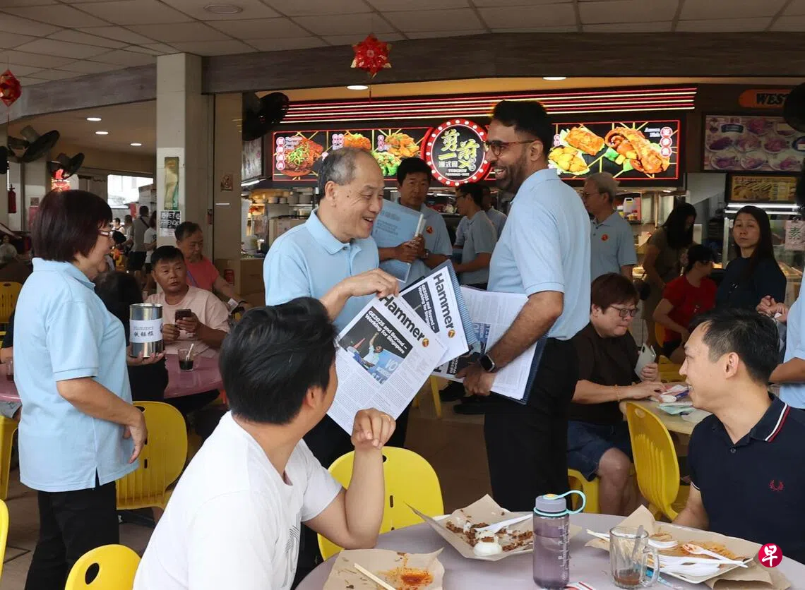 工人党前秘书长刘程强（图中左）与工人党秘书长毕丹星（图中右）在实龙岗北1道咖啡店贩售《铁锤报》。 （邬福梁摄）