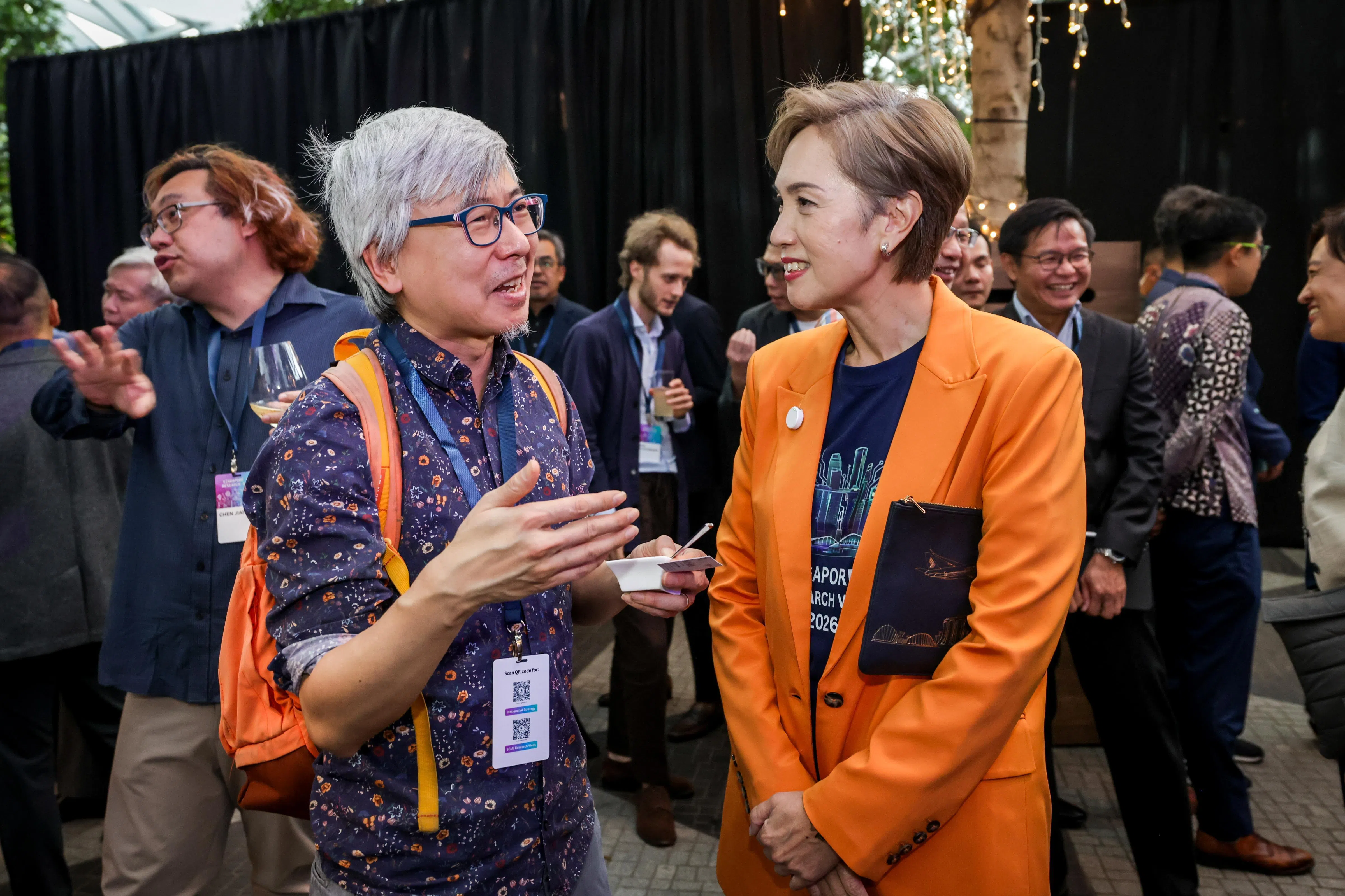 加入我国人工智能客座教授计划的牛津大学统计机器学习教授郑宇怀（左）认为，在地缘政治愈发动荡的时候，新加坡能为人工智能发展提供一个中立且稳定的“避风港”。图为他星期六出席新加坡人工智能研究周晚宴时，与数码发展及新闻部长杨莉明（右）寒暄。（叶振忠摄）