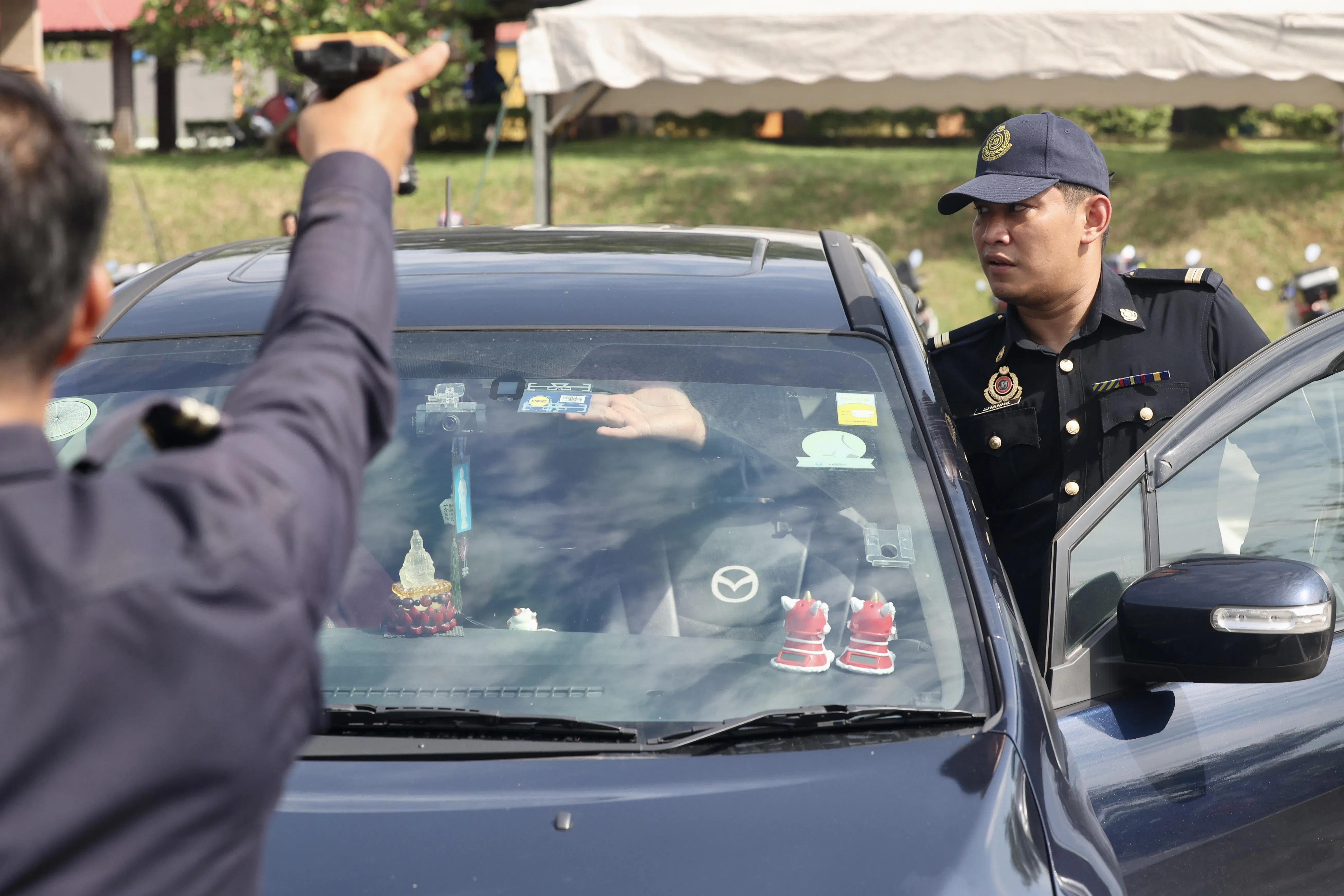 新山旧哥文茶路南区陆路交通学院的陆交局官员，正在协助车主张贴VEP无线射频识别标签，并用扫描仪测试，确保标签张贴位置合适。（陈斌勤摄）