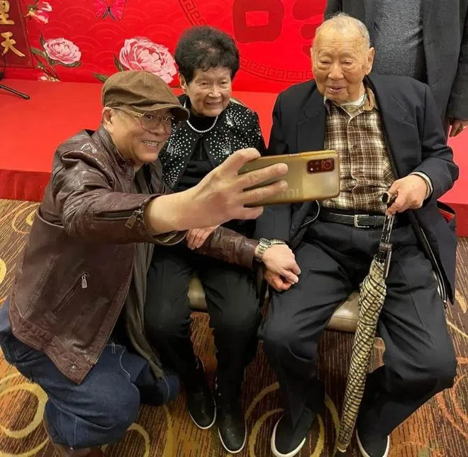 欧阳震华（左一）蹲下与寿星翁（右一）夫妇自拍合照。（互联网）