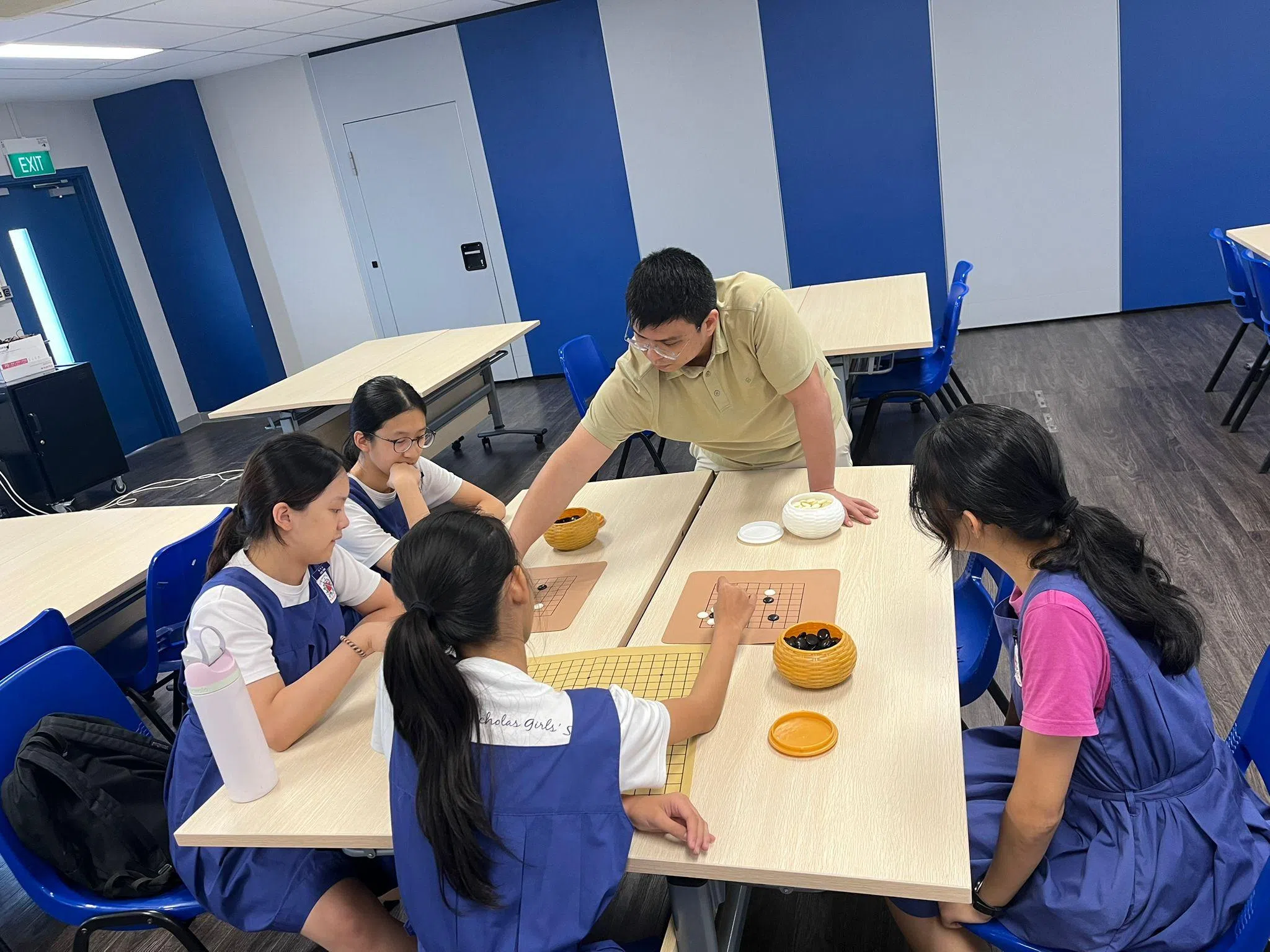 在围棋工作坊中，人文部老师邓祖威（中）指导学生下围棋。（圣尼各拉女校提供）