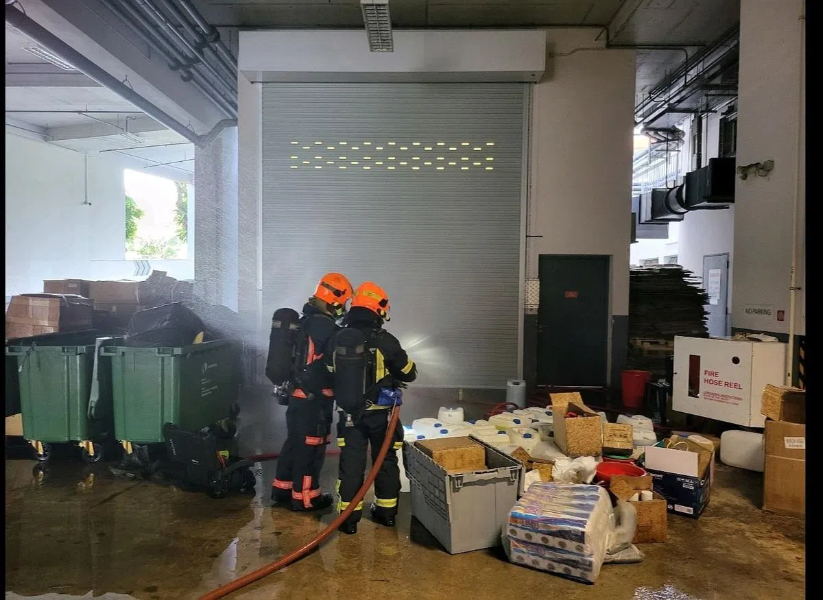 民房人员用水枪稀释垃圾压缩房探测到的氯蒸汽。（取自新加坡民防部队面簿）