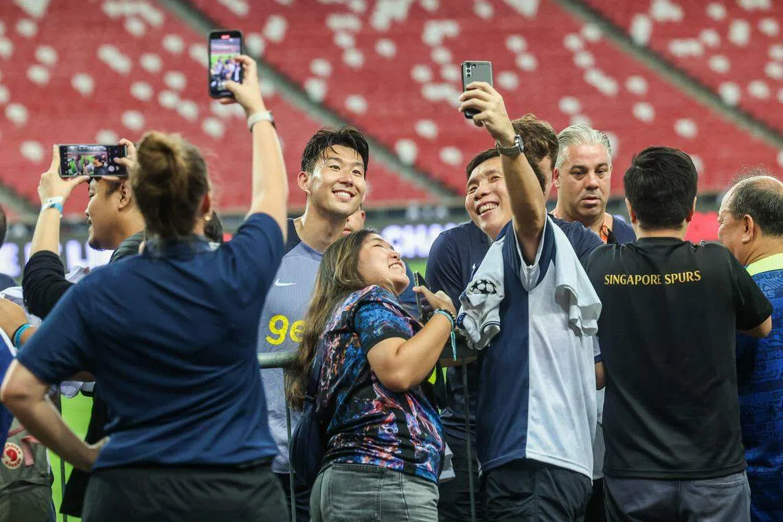 孙兴慜（中）星期二（25日）结束公开训练后与球迷合影留念。（陈斌勤摄）