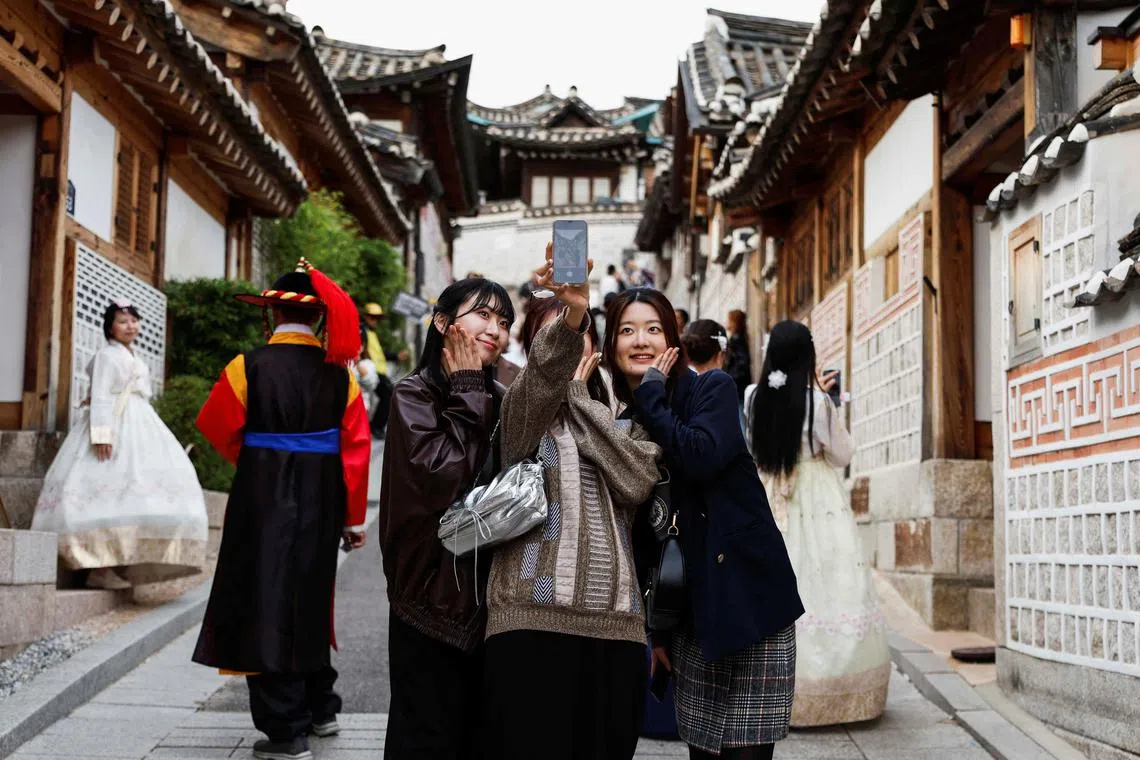 韩国热门旅游景点北村韩屋村现有居民6100人，但每年吸引游客约600万人次。图为游客在古镇内自拍。（路透社）