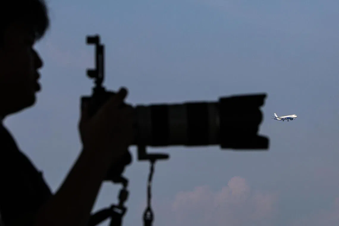 长焦镜头对准天空，摄影者耐心等待飞机进入画面。（关俊威摄）