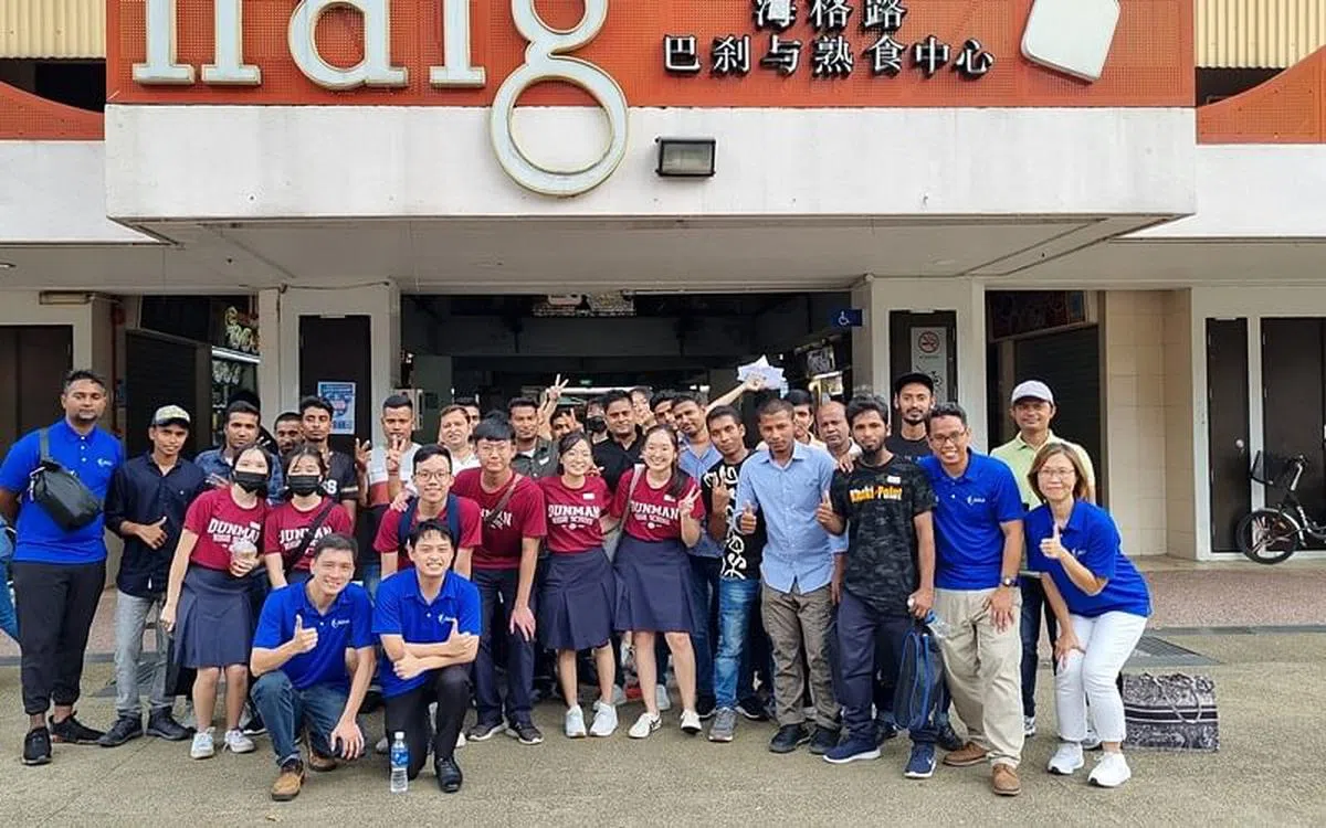 德明政府中学生陈靖霓（第二排左五）与同学和客工一起参观芽笼士乃，透过介绍本地美食、服装和童年玩具等，让客工认识本地文化历史。（人力部提供）