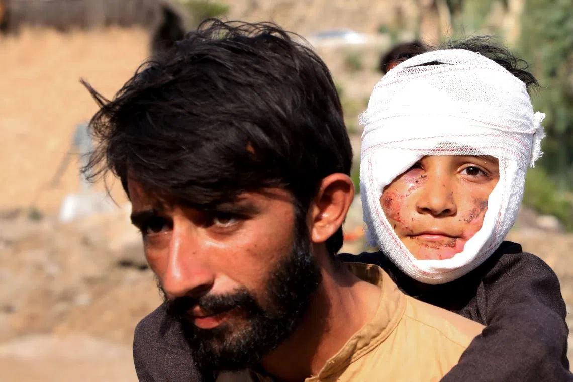 阿富汗东部库纳尔省（Kunar）重灾区，几乎所有房屋都被夷为平地。图为当地一名男子背着一名受伤的男孩。（法新社）