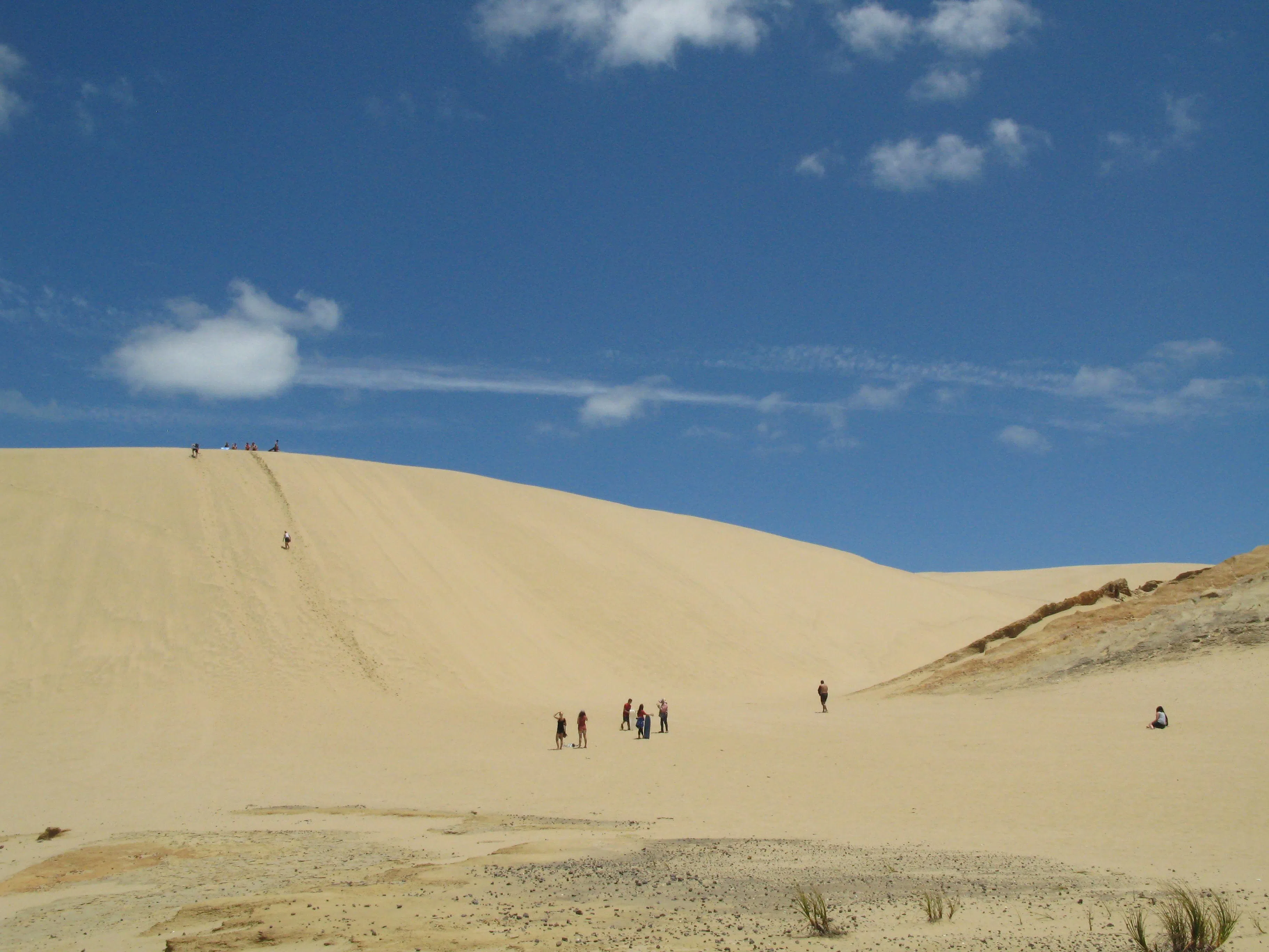 在蒂帕基沙丘上，游客俯伏在滑沙板上，沿着金色的滑坡滑下来，非常刺激。（陈静芳摄）