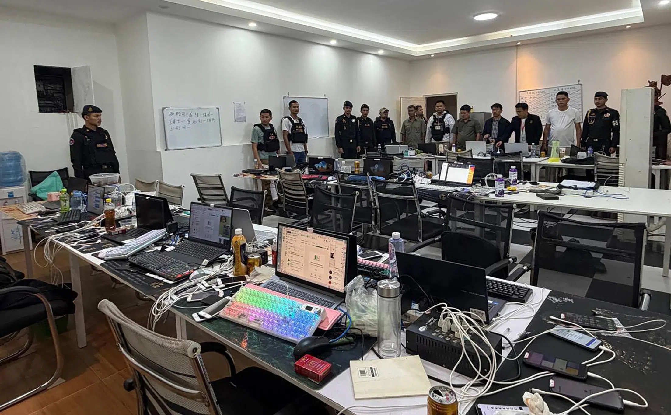餐馆内的一间房被改造成办公场所，桌面陈列着大量用于网络诈骗活动的笔记本电脑和手机。（取自高棉时报脸书）