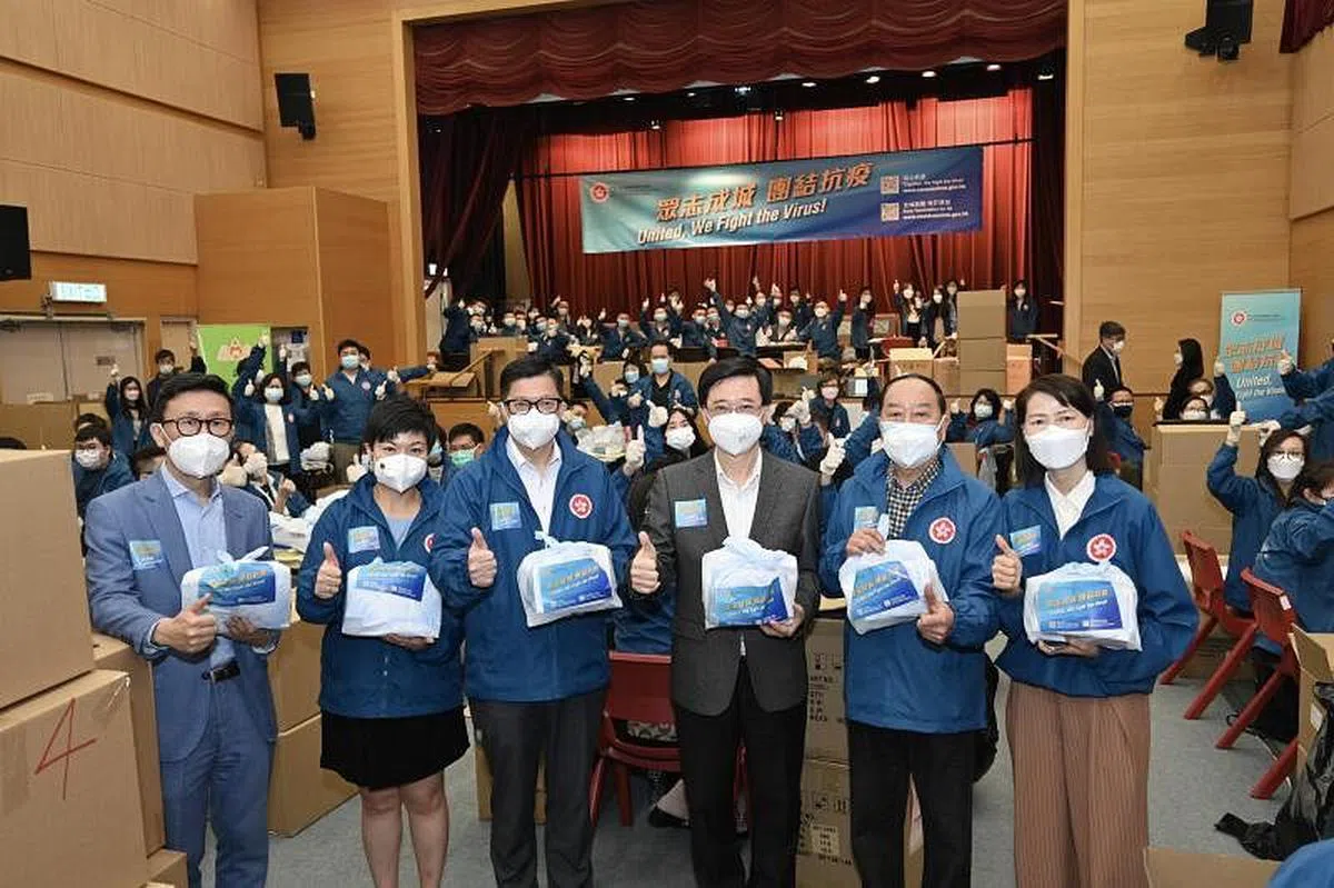 李家超3月30日分别到访深水埗丽阁社区会堂和沙田香港文化博物馆的“防疫服务包”包装中心，为公务员和社会各界义工打气。图为李家超（右三）和保安局局长邓炳强（右四）在丽阁社区会堂的“防疫服务包”包装中心与一众工作人员合照。 （中通社）