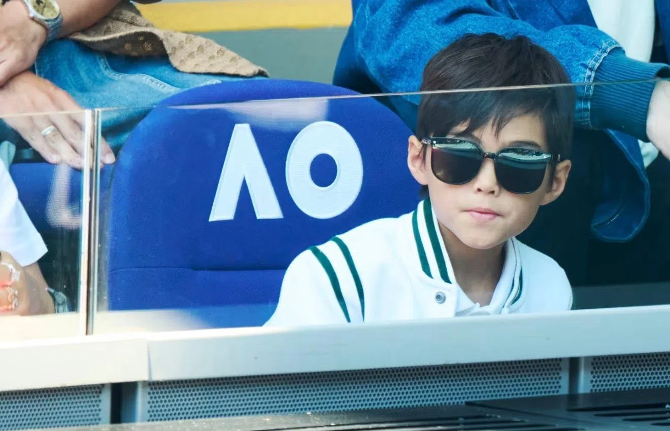 Romeo身穿白色运动休闲外套，戴着墨镜坐在观众席。（互联网）