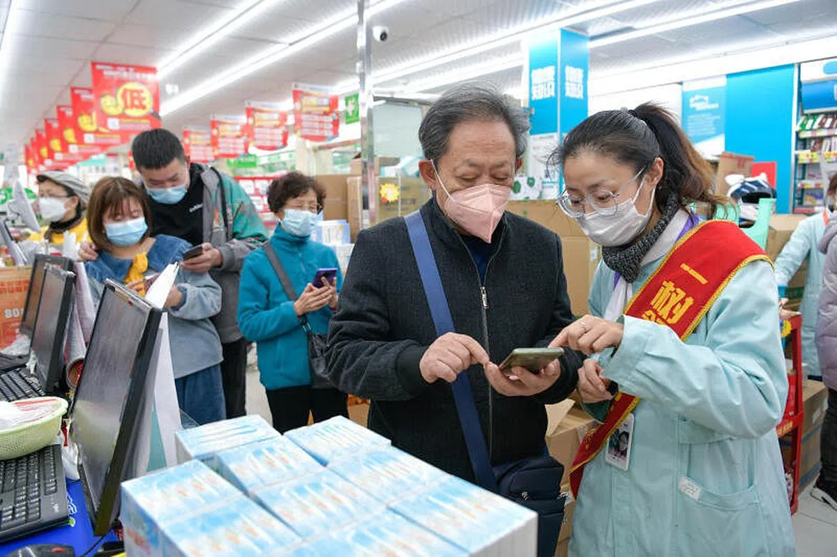 贵州免费发放退烧药等药品给民众。12月24日，贵州贵阳市云岩区一家药店的工作人员指导市民如何服用退烧药。（新华社）