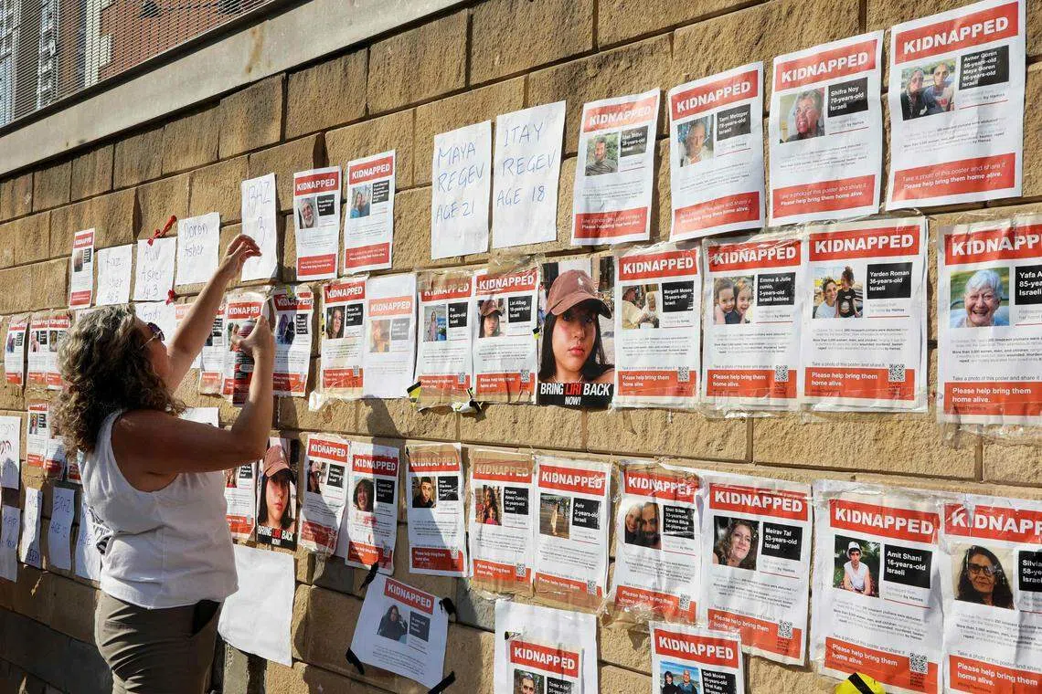 哈马斯掳走以色列人质后，人质亲属和支持者在一座军事基地外张贴人质照片。（法新社）