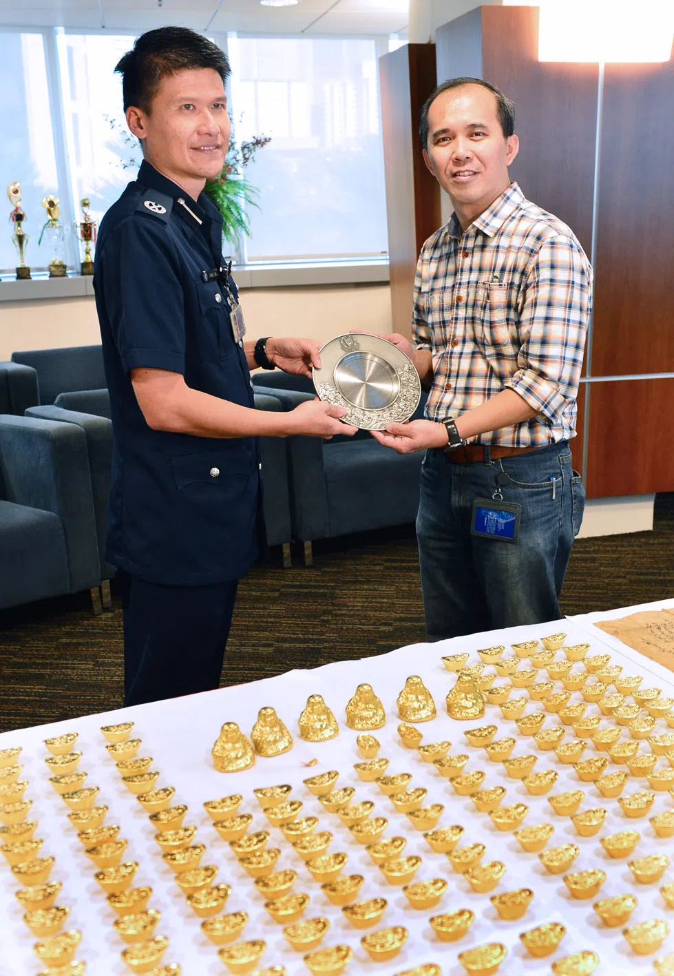 本地新闻副主任陈凯松曾助警破12万元金元宝诈骗案，凭20多年跑新闻的经验，提醒商人朋友不要掉进骗局，并报警设埋伏捉拿罪犯。陈凯松（右）于2014
年11月26日从中央警署署长陈新兴手中接获警方颁发的锡盘奖状。（档案照片）