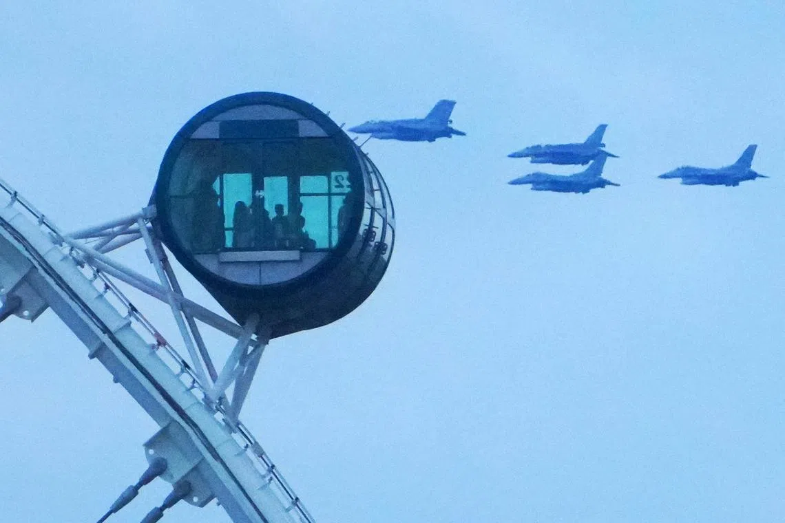 国庆军机表演从新加坡摩天轮上方掠过，形成难得一见的景观。（何家俊摄）