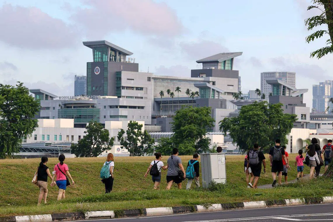 由于跨境巴士堵在兀兰中心路（Woodlands Centre Road），不少乘客选择下车步行到关卡，有者一家出行、拉着行李。（陈渊庄摄）