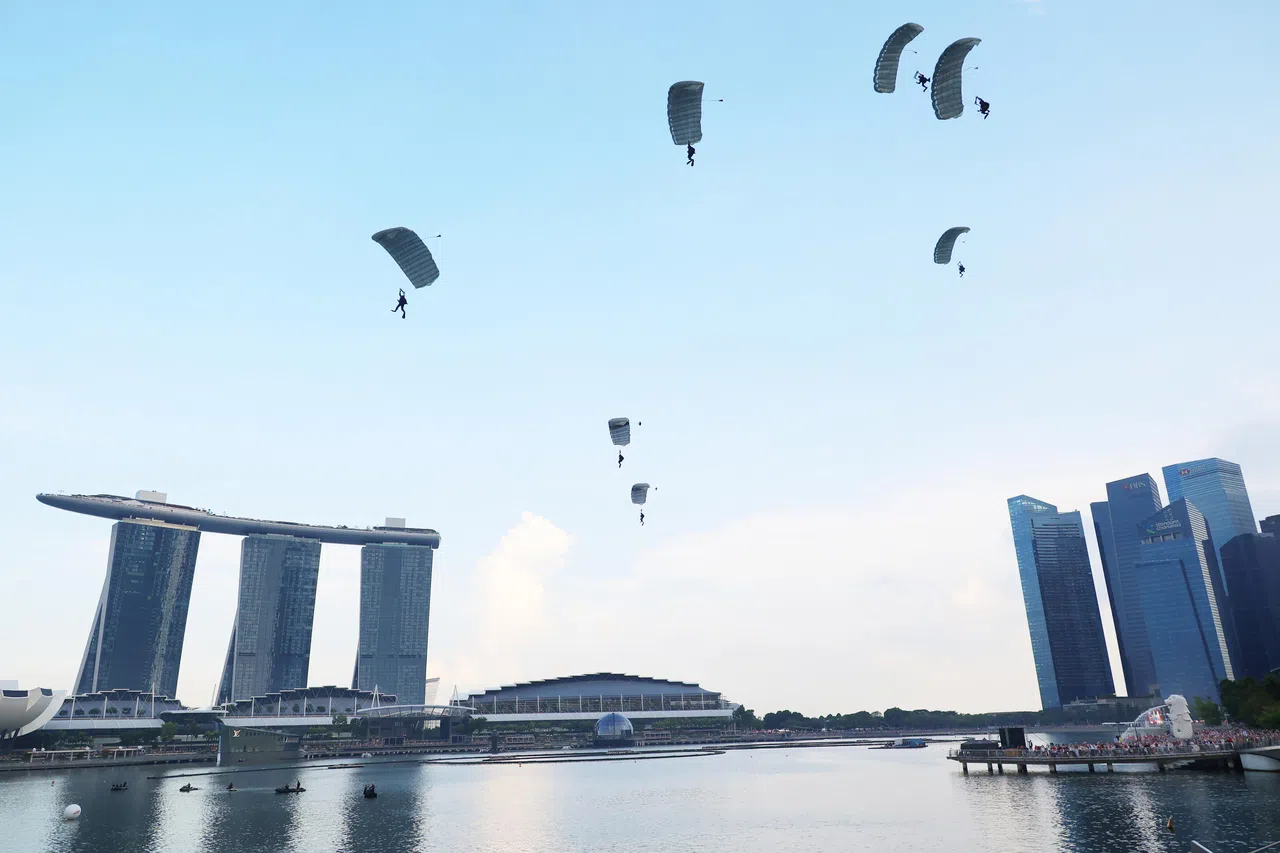 七名海军蛙人从6000英尺高空跃下，滑翔至滨海湾水域，并以默契的入水动作，为聚集在滨海湾周边的上万名公众，近距离献上一场视觉震撼。（李天錡摄）