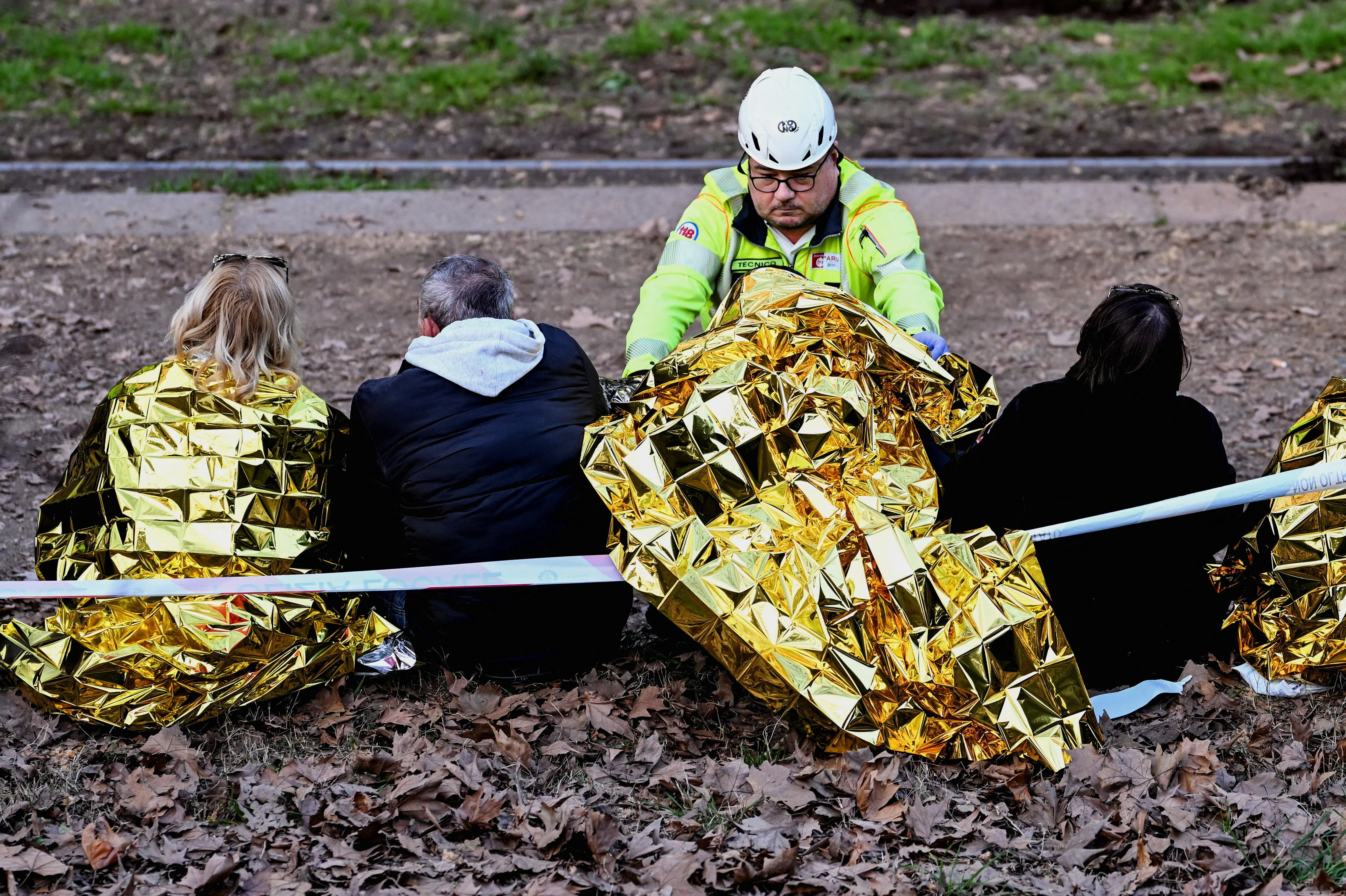 电车脱轨后，一些伤者坐在路边接受初步医疗救助。（路透社）