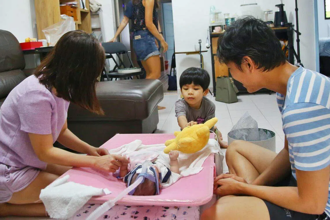 四岁的施佁鍕（中）跟妈妈一起到王梓全（右）和张绮恩（左）的家探访，为他们打气。佁鍕好奇地打量着在躺椅上的彦喆，不时尝试用手上的玩偶逗他。（特约陈福洲摄）