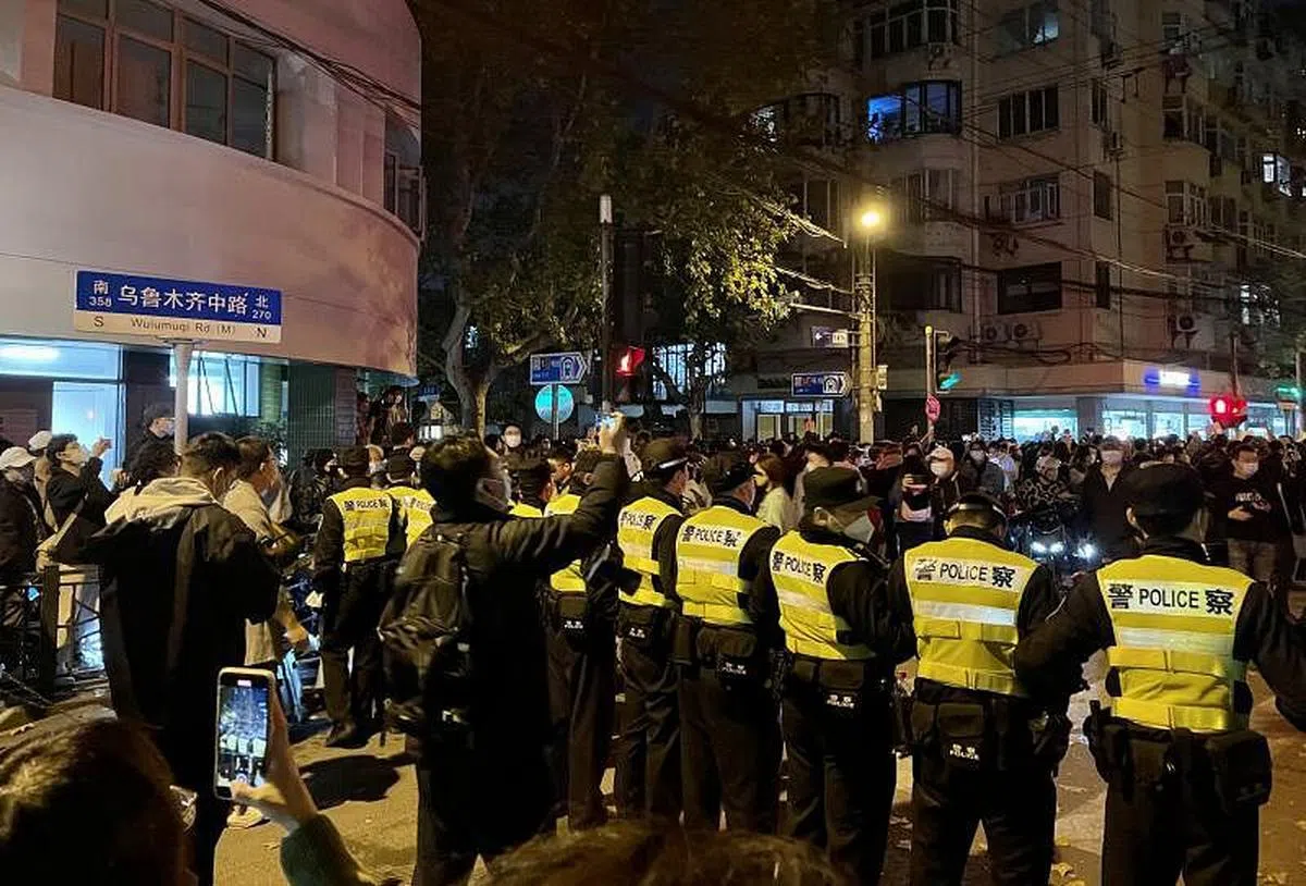  星期天傍晚，数十名警员到乌鲁木齐中路增援。警方组成人墙扩大封锁，驱赶现场民众。（《联合早报》记者摄）