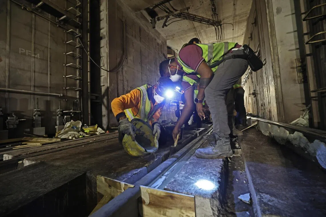 工程人员为新轨道灌注快速凝固混凝土，使轨道在短时间内稳固就位。（陈渊庄摄）