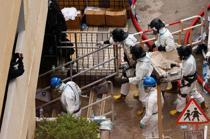 警方人员12月1日抬着一名在火灾损毁楼栋内发现的遇难者遗体。（路透社）