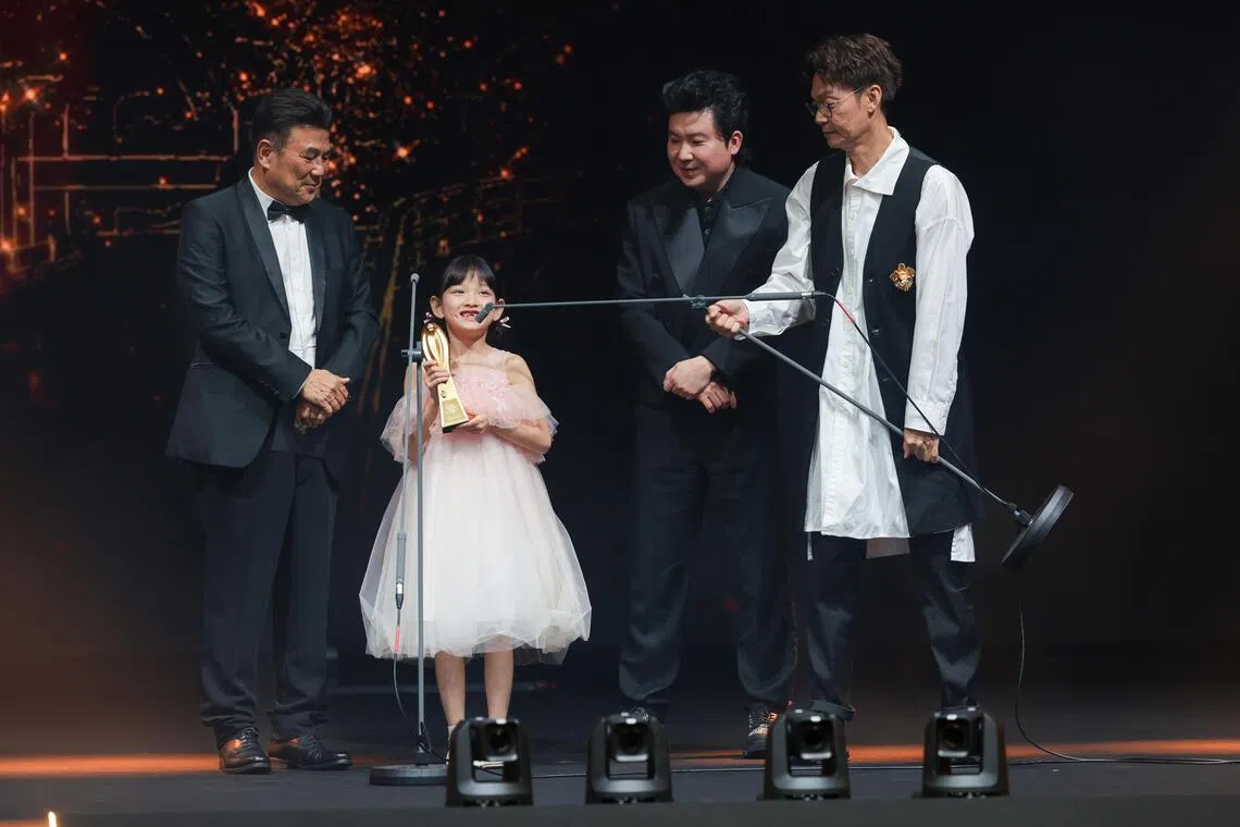 李国煌（右一）提起麦克风支架，让约一米高的最佳新人奖得主李珞桉（左二）致辞。（白艳琳摄）
