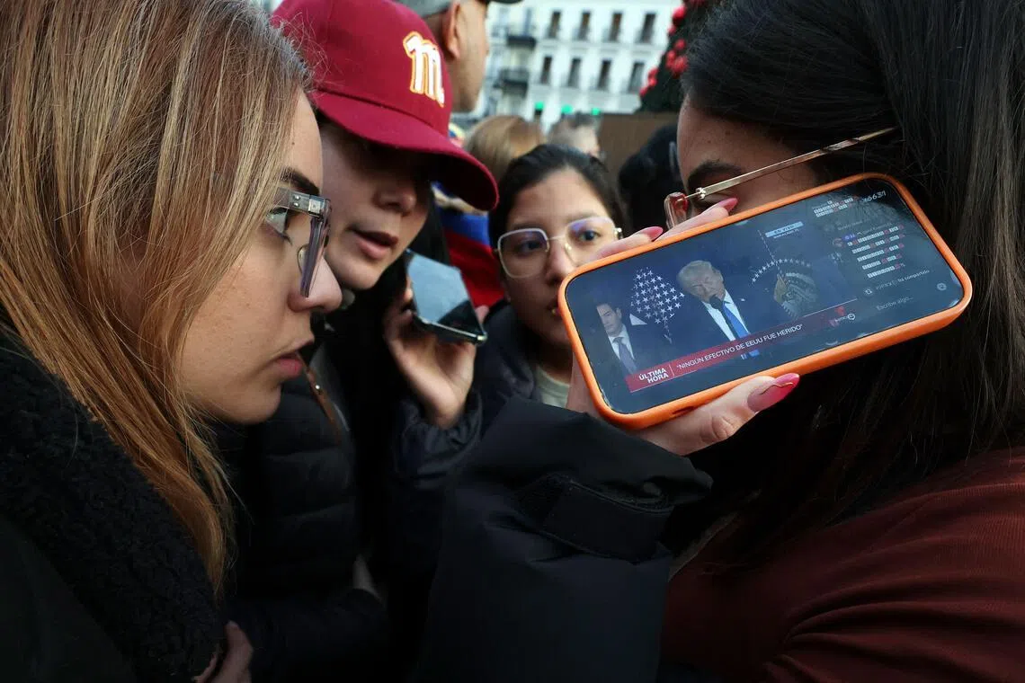 1月3日，居住在西班牙的委内瑞拉公民聚集在马德里太阳门广场，用手机观看美国总统特朗普的新闻发布会。（法新社）