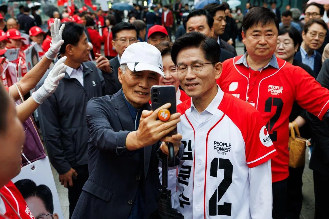 5月16日，韩国执政党国民力量候选人金文洙（右）在城南市板桥区拉票时与支持者合照。（彭博社）
