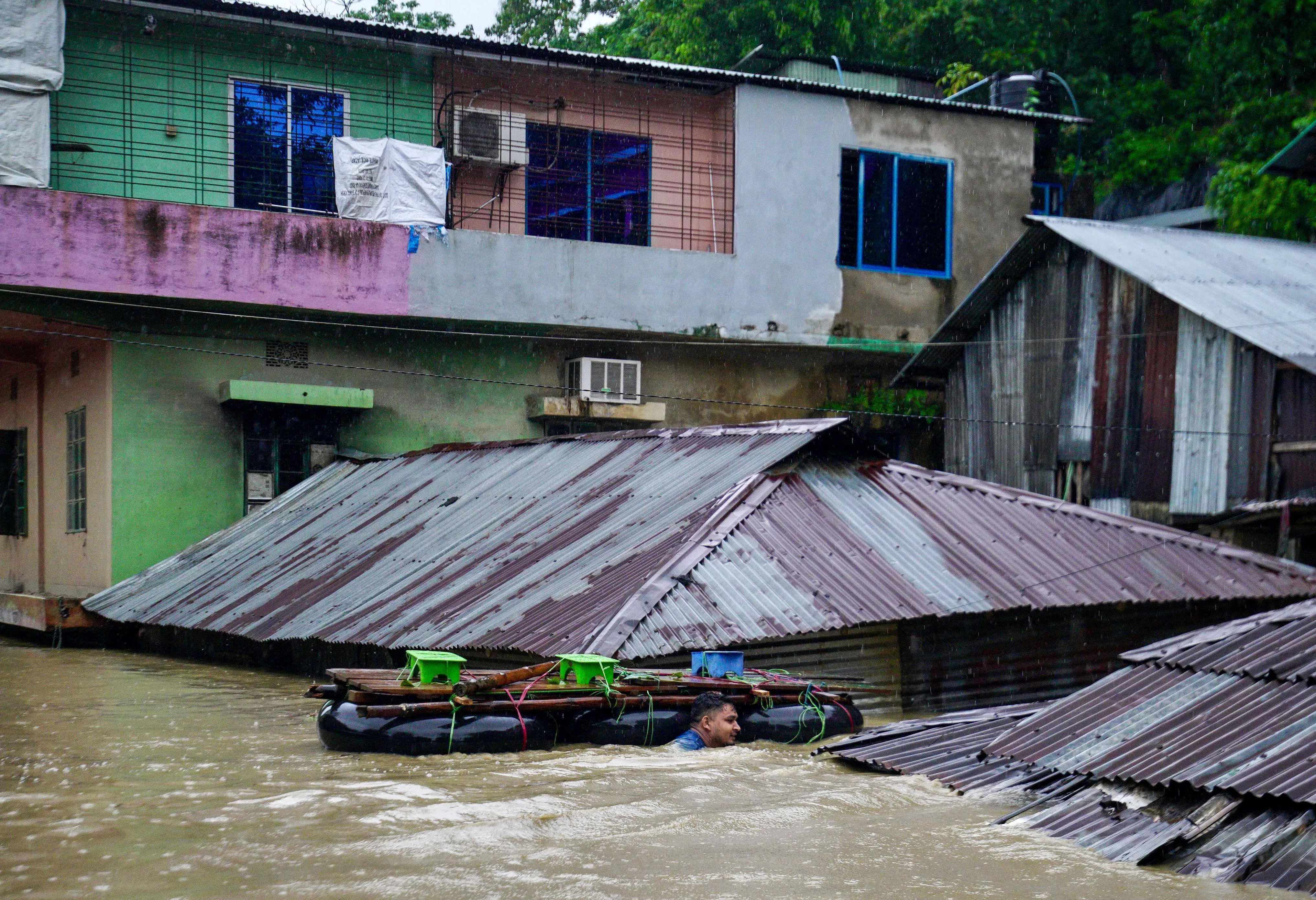 7月8日，孟加拉国班达尔班镇遭遇暴雨袭击，一名男子扛着一艘简易船趟过洪水淹没的地区，营救受困居民。（法新社）