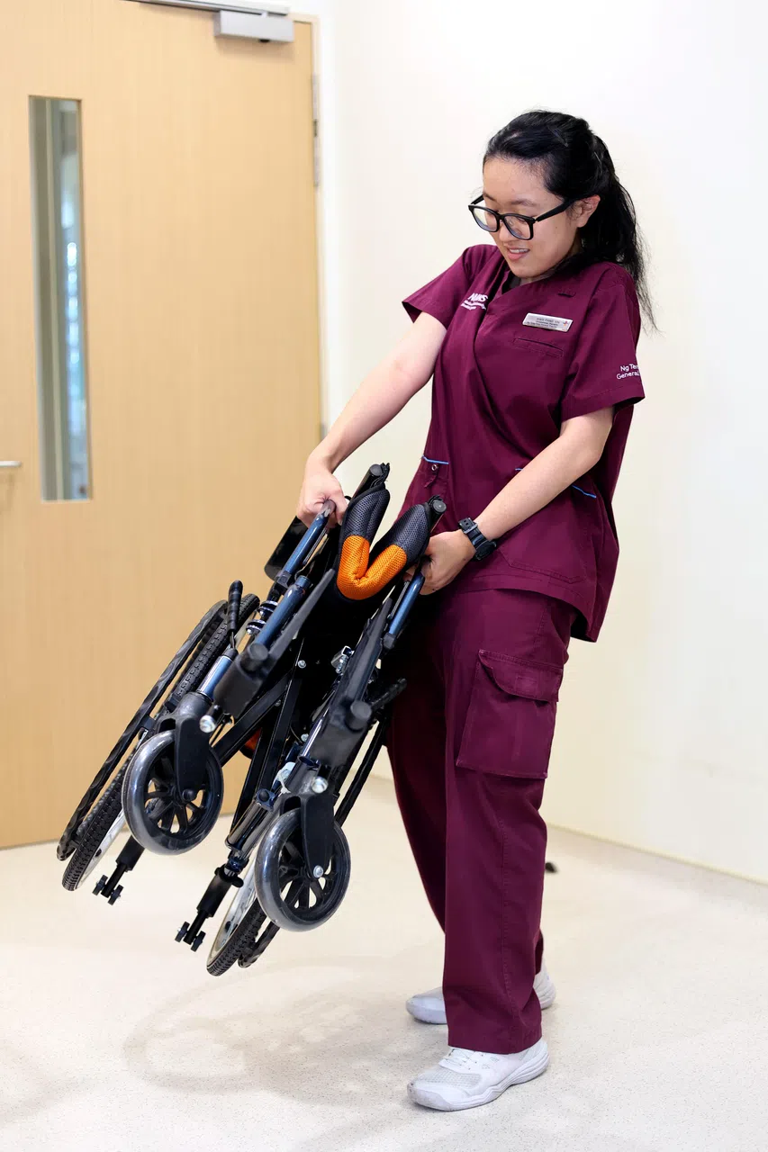 抬起轮椅的错误做法：双手握推柄直接抬起。（龙国雄摄）