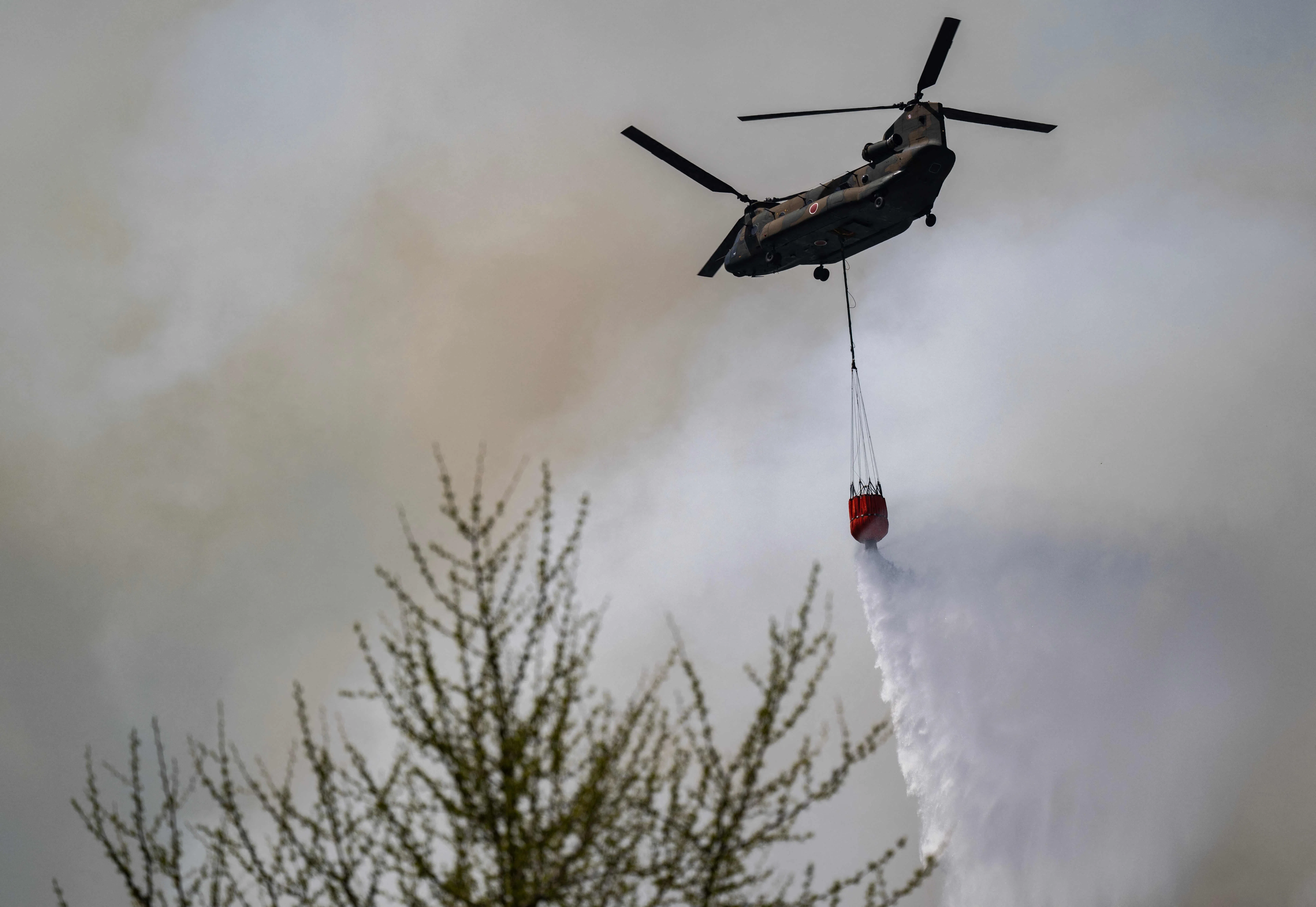 日本自卫队一架直升机星期天（4月26日）在岩手县大槌町附近洒水灭火。（法新社）