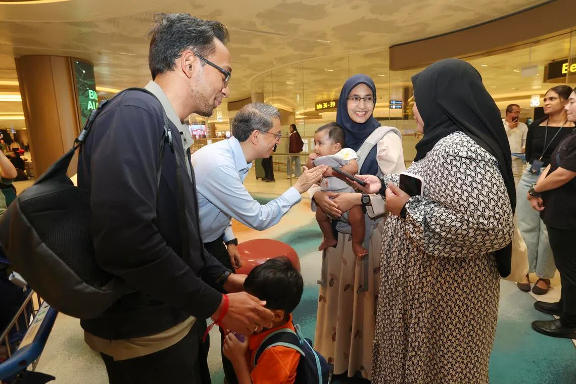 费绍尔副教授（左二）星期五清早到樟宜机场，迎接回国的新加坡人，包括从沙特阿拉伯布赖代（Buraydah）返新的医药研究员锡斯万德（Siswand Ali，37岁，左一）、妻子爱莎（35岁，化学家，右二），以及他们的4岁和六个月大儿子。（郑一鸣摄）