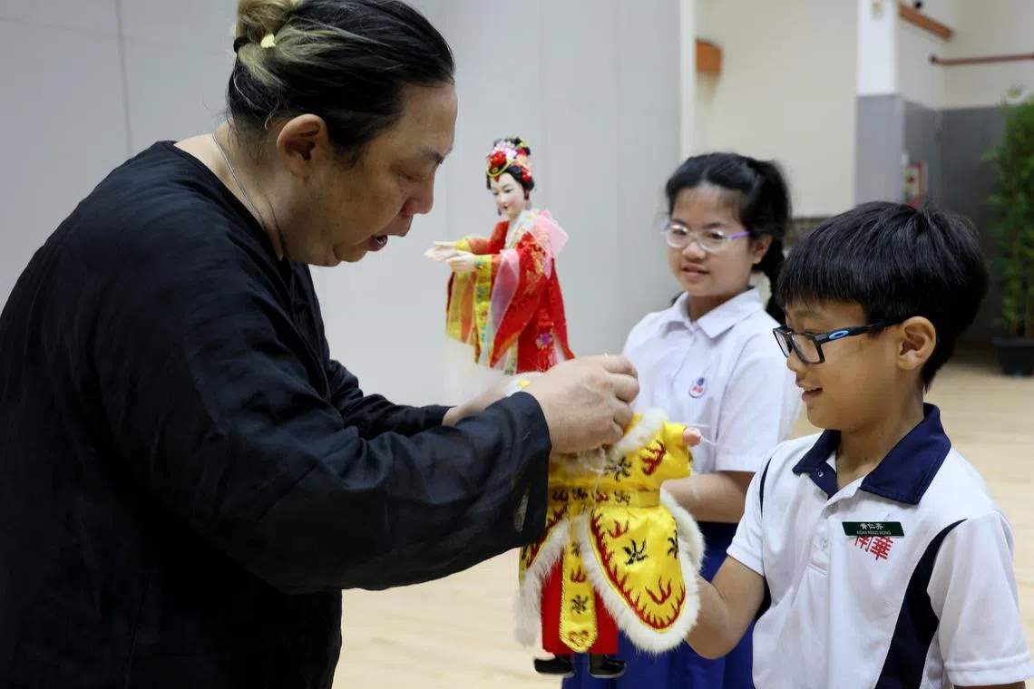 猴纸剧坊艺术总监何家伟巧妙（左）教导学生如何操作传统偶。（龙国雄摄）
