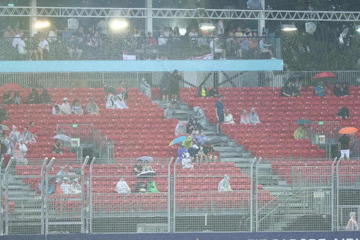 滨海湾赛道在第三场练习赛前下起大雨，观众纷打伞或换上雨衣。（张思庆摄）
