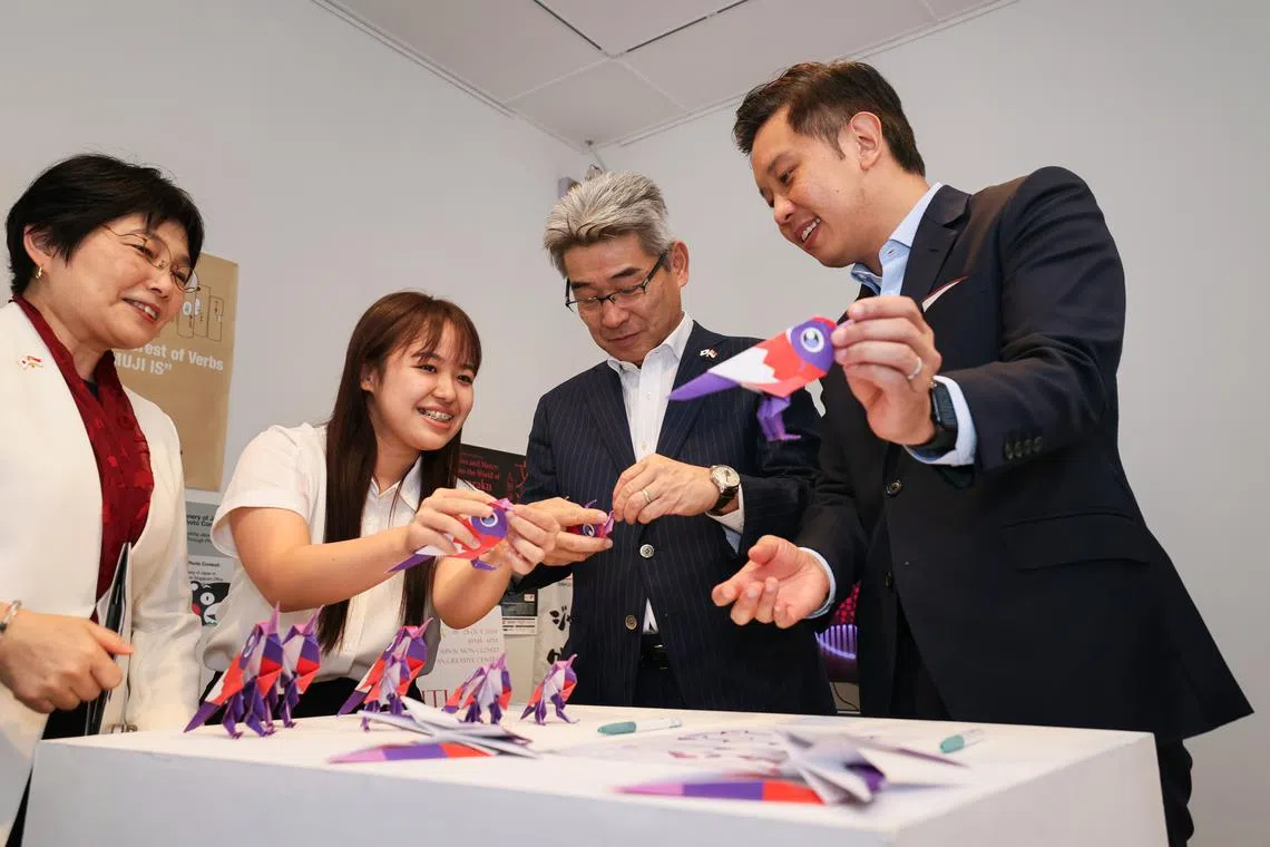 贸工部兼文化、社区及青年部政务部长陈圣辉（右一）和日本驻新加坡大使石川浩司（右二）在工作人员的指导下，完成“Sunny”折纸。（龙国雄摄）