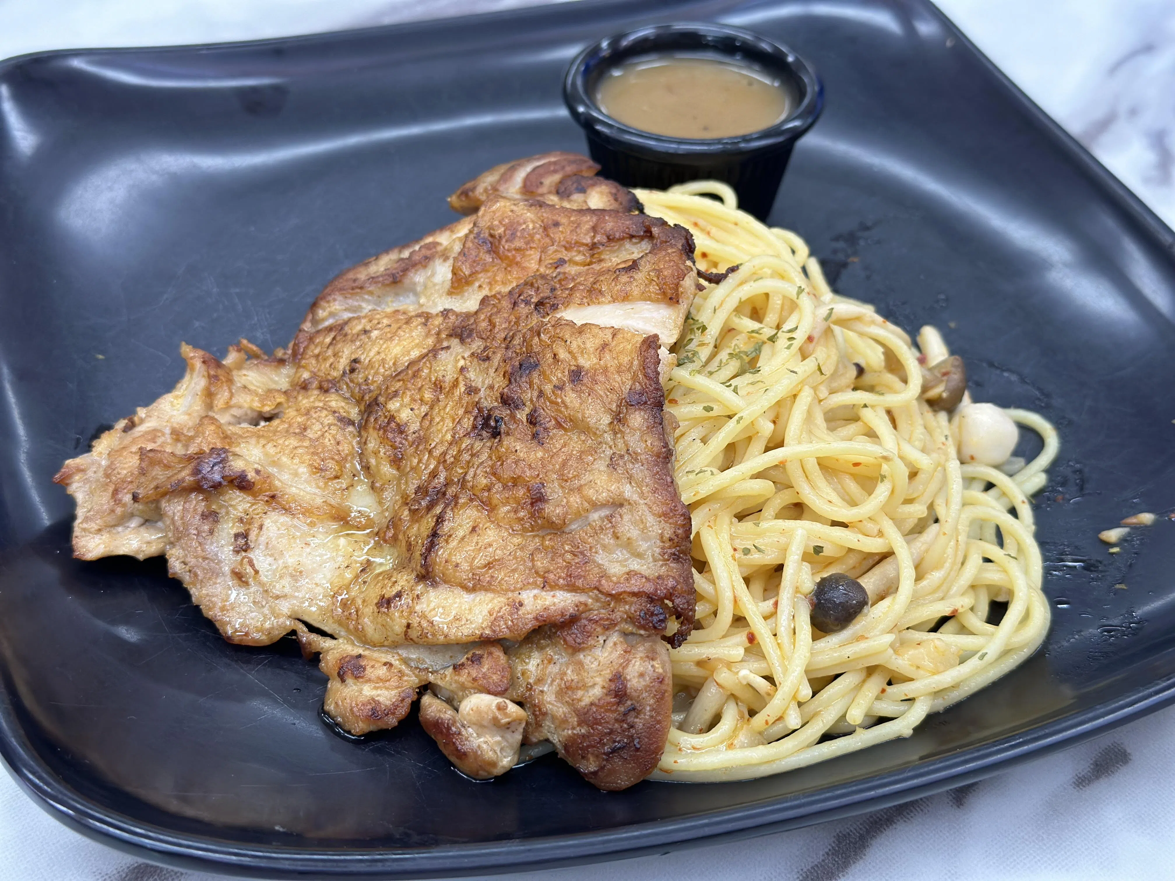 蒜香意面配烤鸡扒，面条裹满浓郁的蒜香，具有微辣香气；烤鸡扒外皮酥脆，内里多汁，保留了鸡肉的鲜美与嫩滑。（叶晓虹摄）