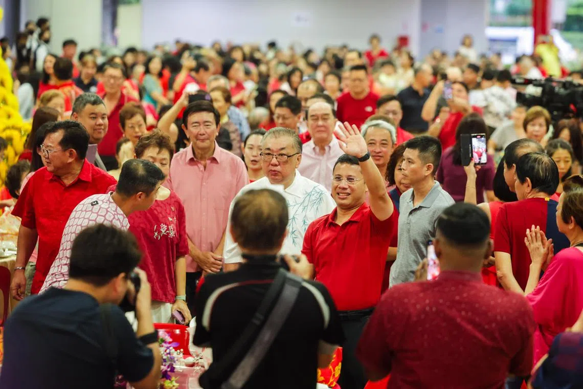 国家发展部长李智陞（红衣举手者）在裕廊西农历新年晚宴上，宣布推出私人住宅区乐龄翻新计划。（蔡家增摄）